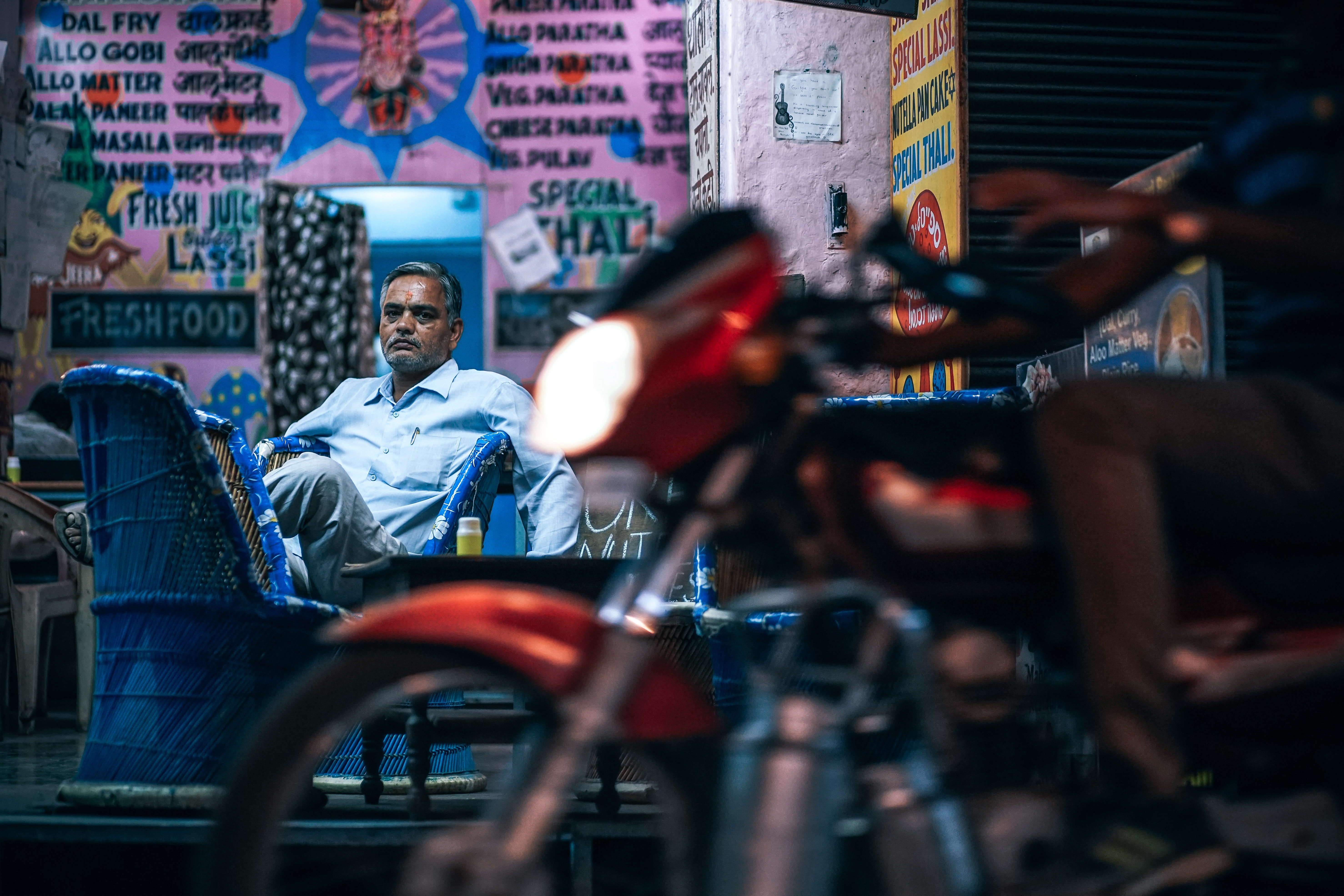 Man in Blue Dress Shirt Sitting on Blue Chair Beside Pink Painted Wall, Action, Retail, Motorcycle, Night, HQ Photo