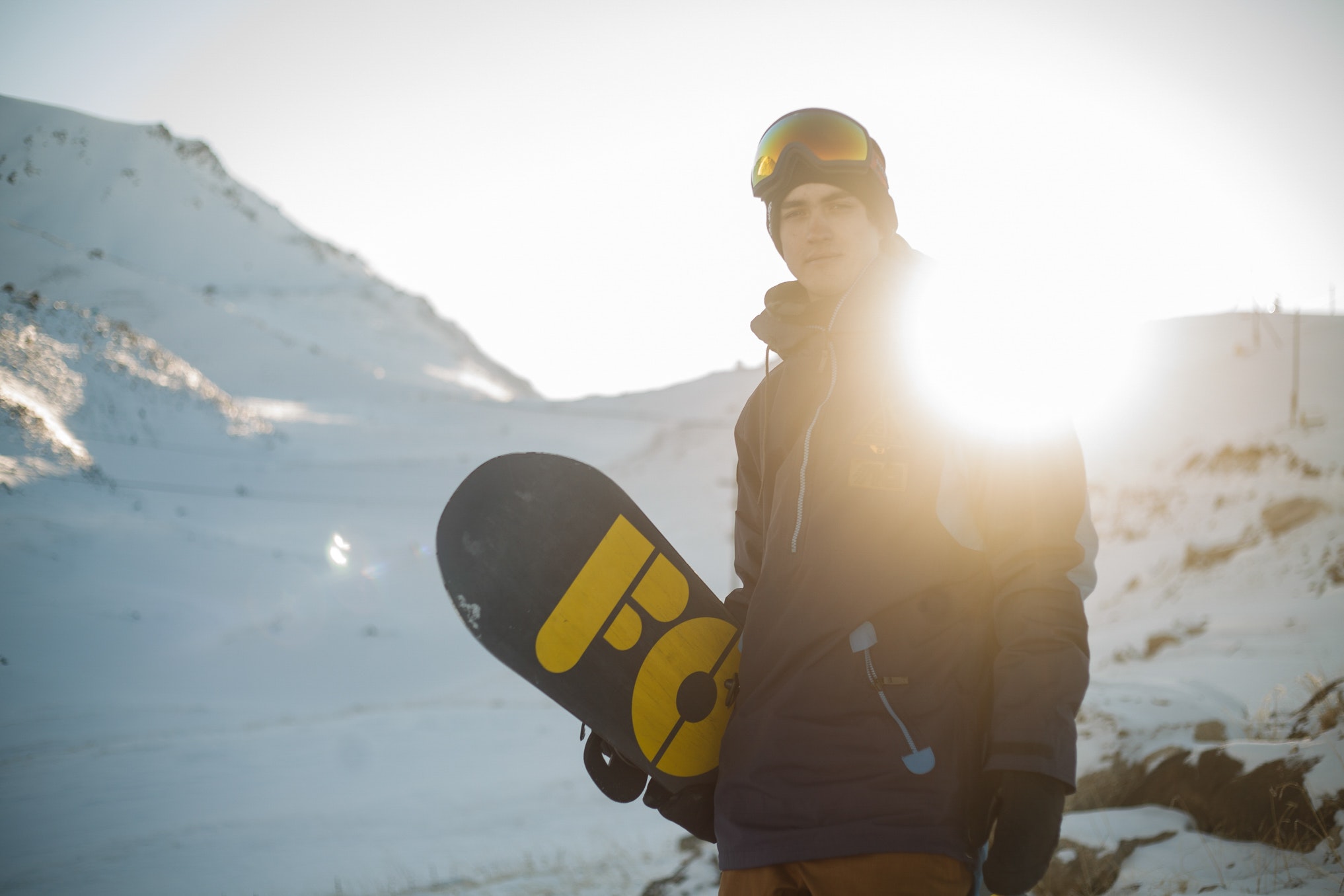 Man in blue pullover hoodie holding blue and yellow snowboard photo