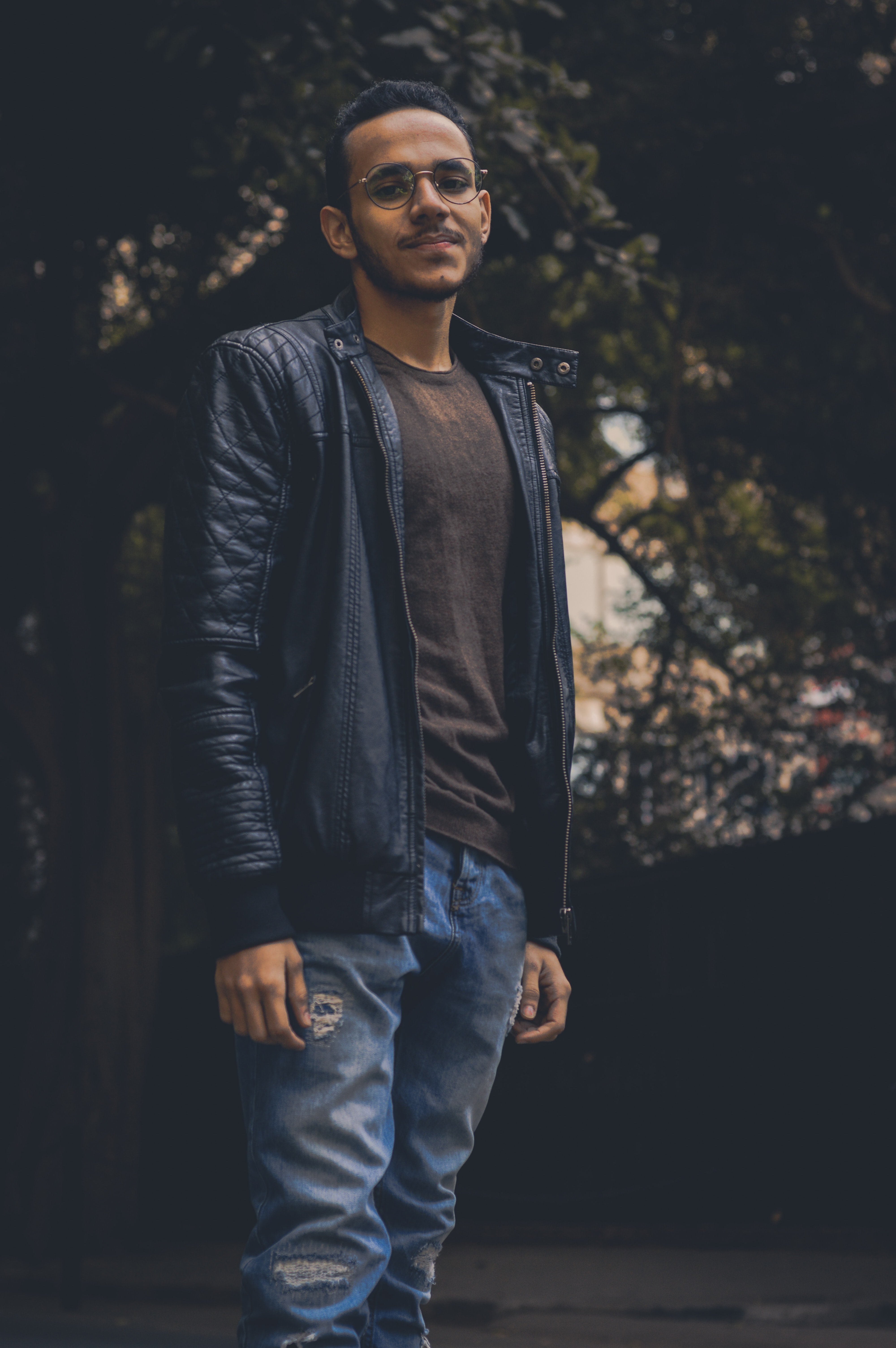 Man in brown shirt and black leather zip-up jacket and blue denim pants photo