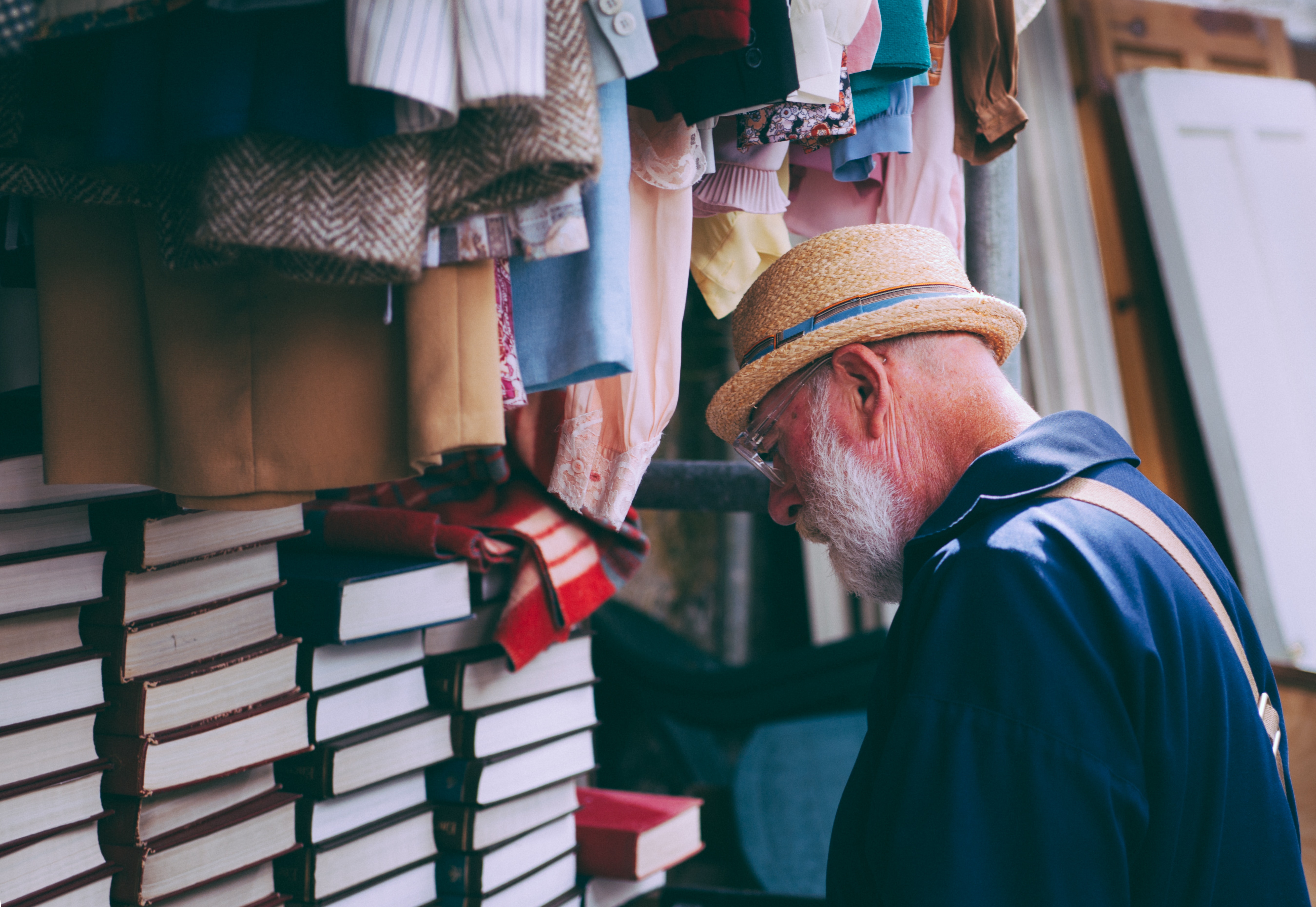 Man in brown sun hat facing black covered piled books photo