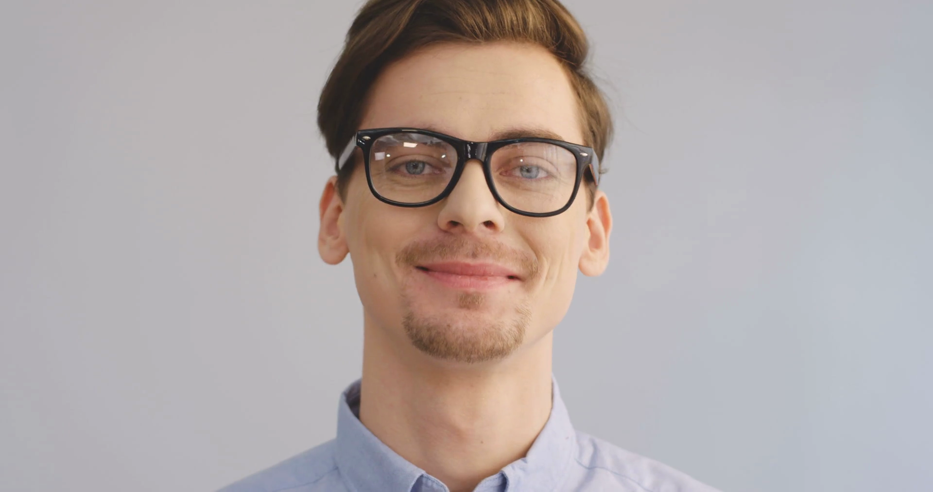 Portrait of the young man in glasses laughing in front of the camera ...