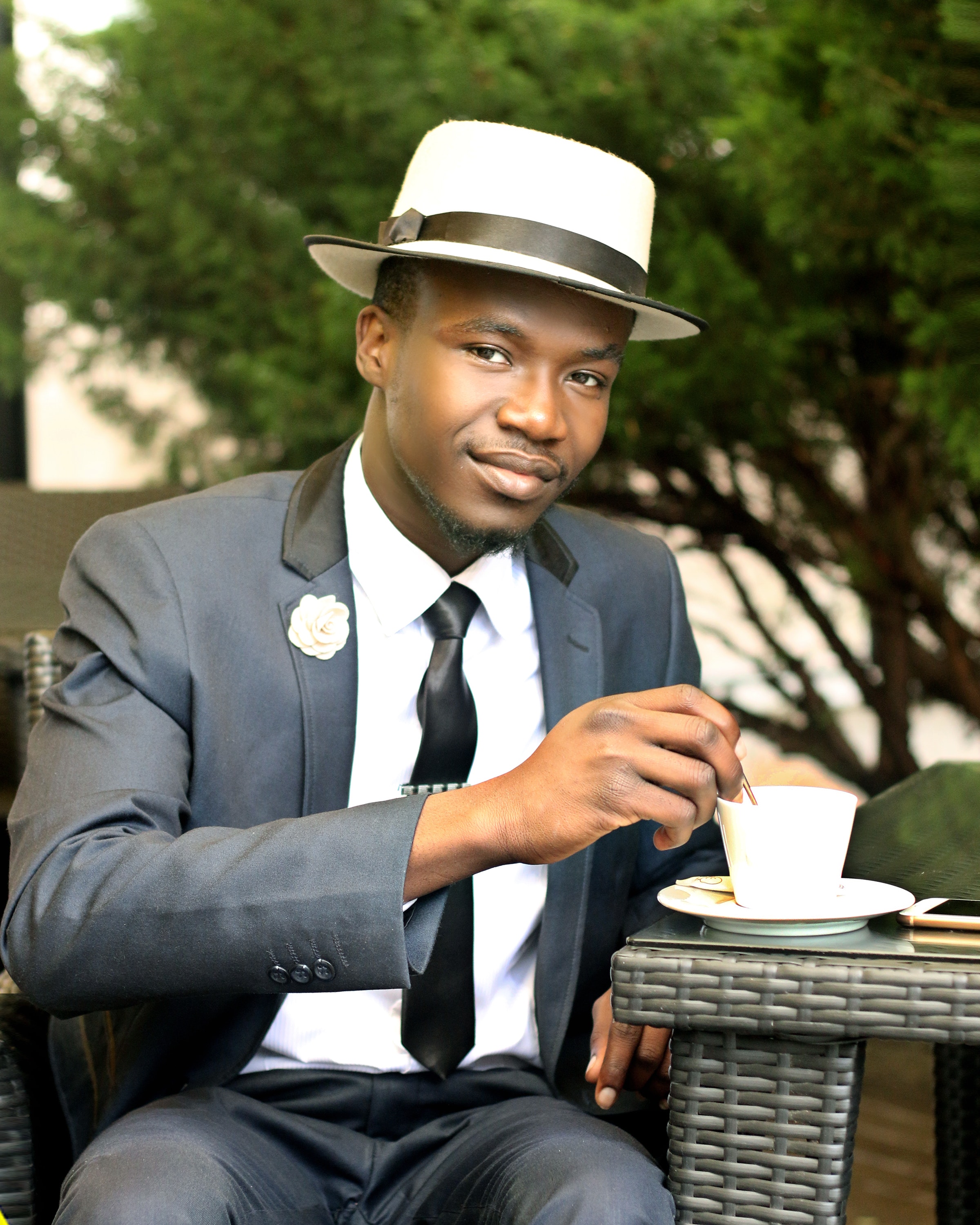 Man in gray formal suit jacket stirring coffee during daytime photo