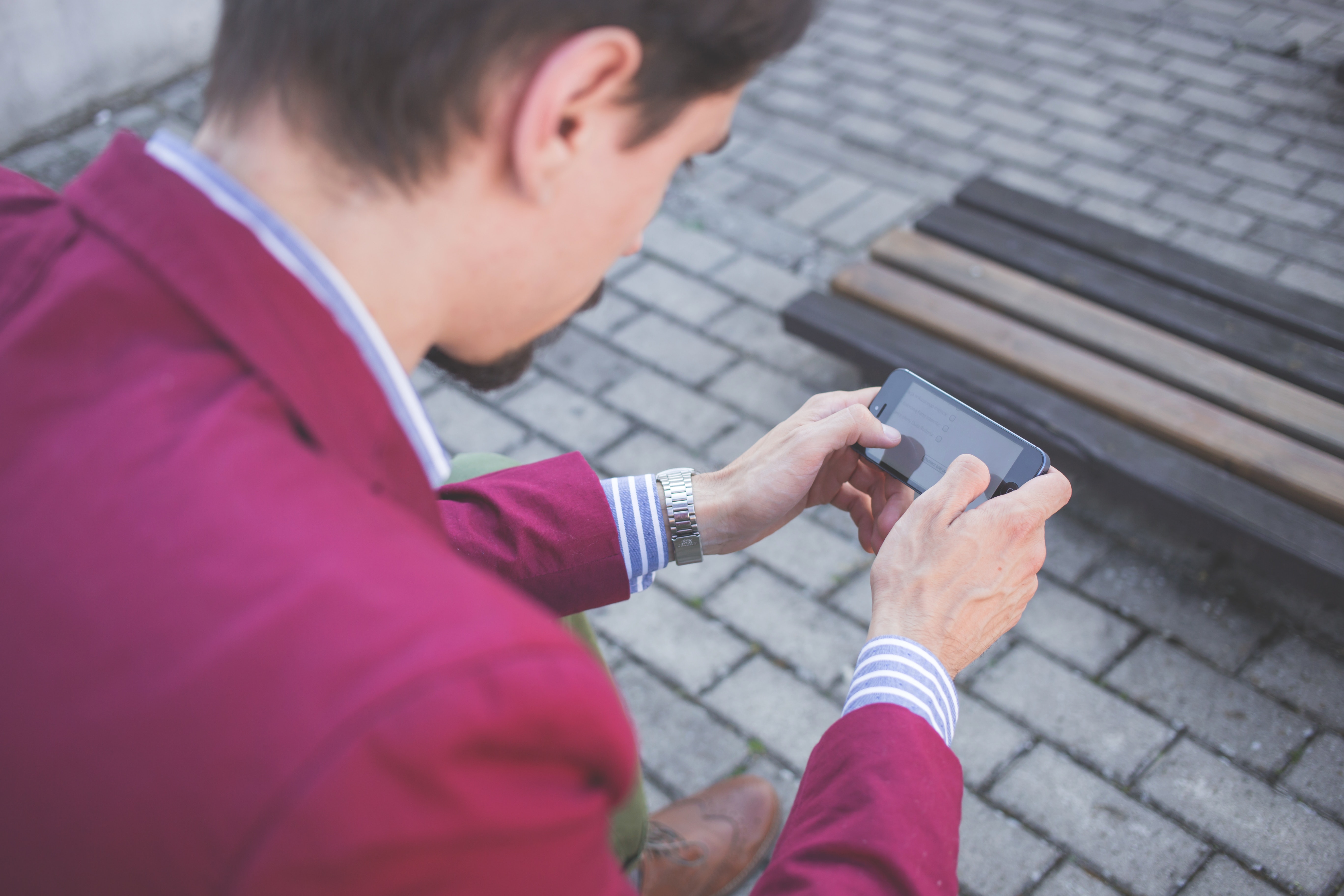 Man in magenta suit jacket holding smartphone with both hands photo