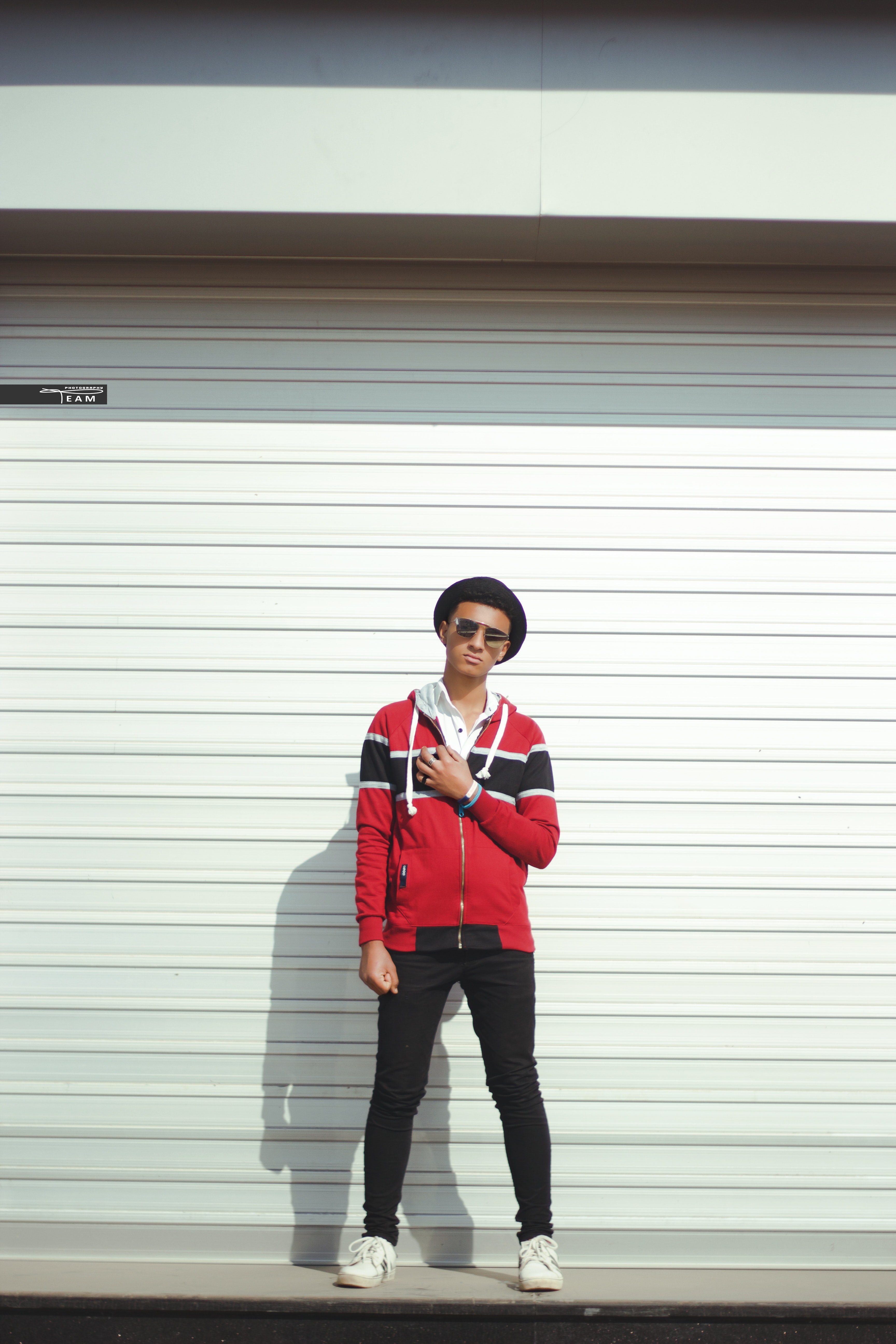 Man in red and black zip-up jacket and black pants with black hat photo