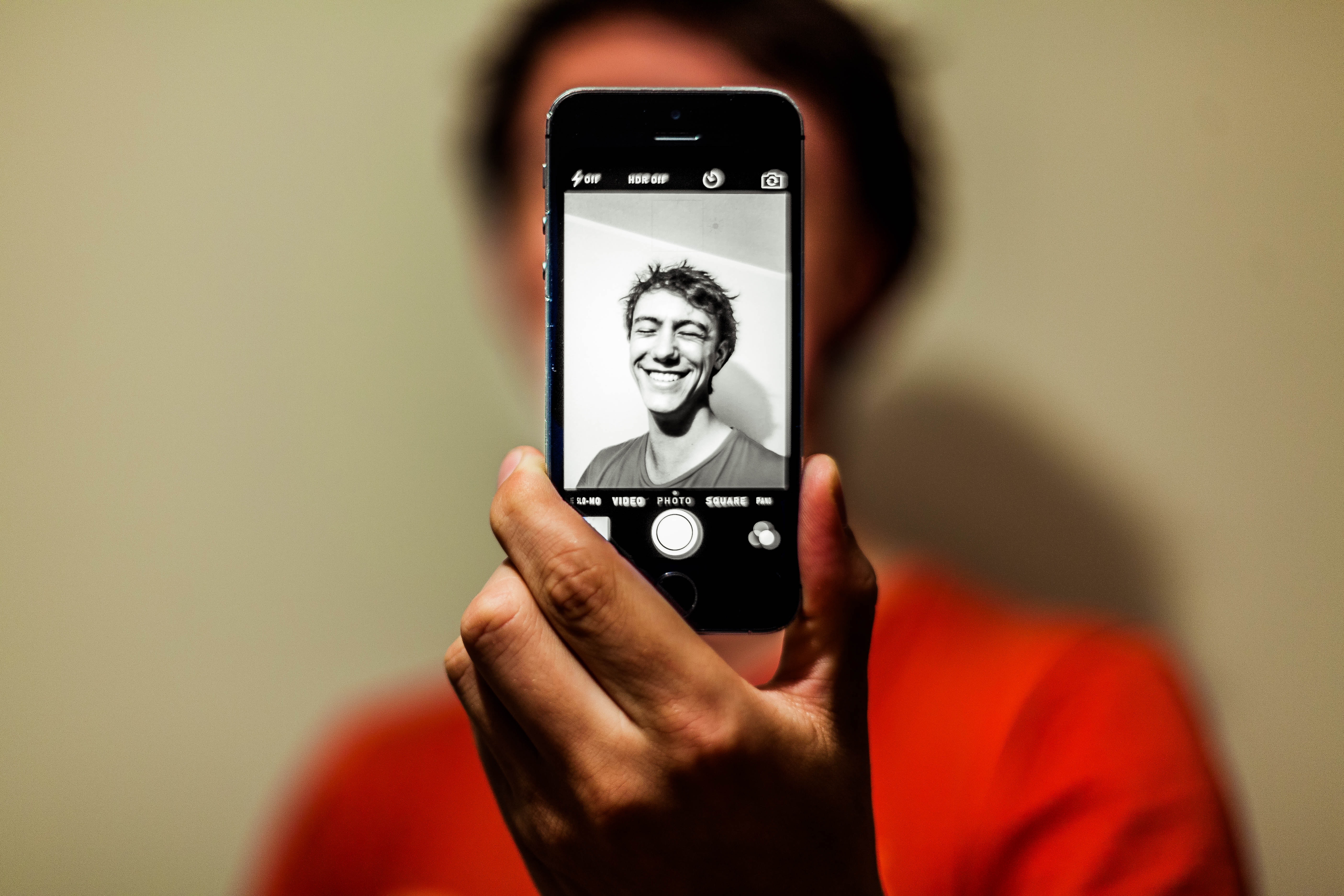 Man in red shirt having selfie on his iphone in grayscale mode photo