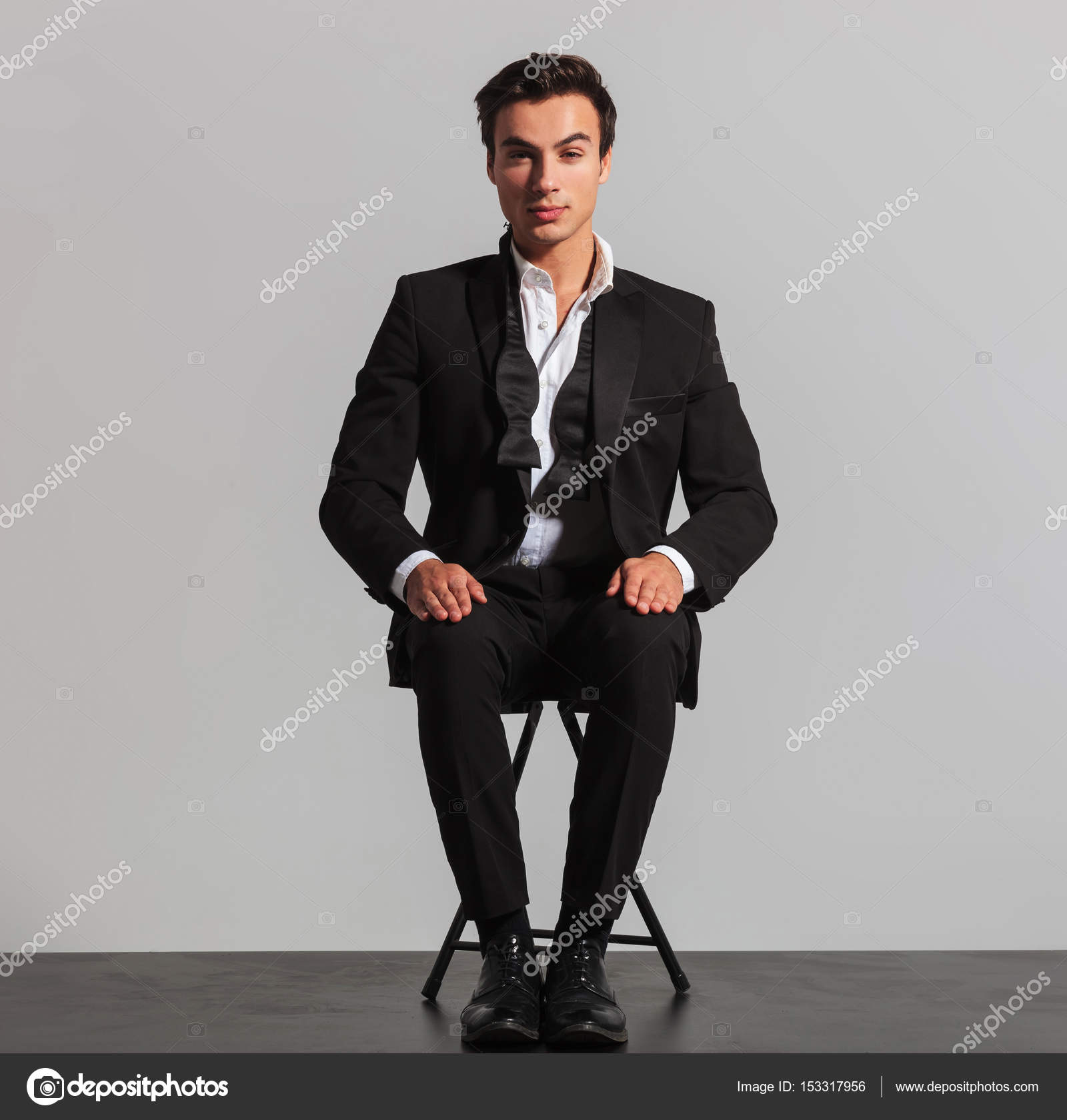 elegant man in suit and undone bowtie sitting on chair — Stock Photo ...