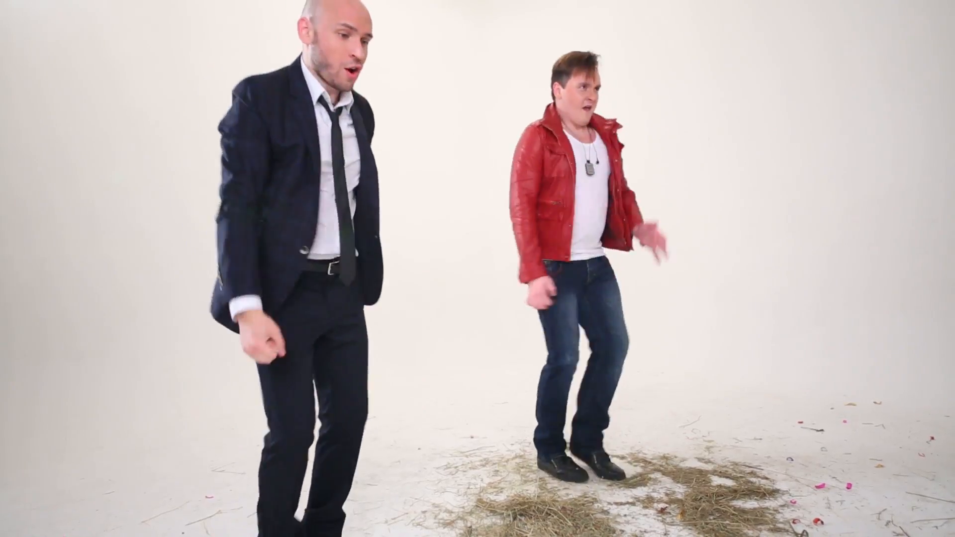 Man in suit and man in red jacket dance on floor with hay in white ...