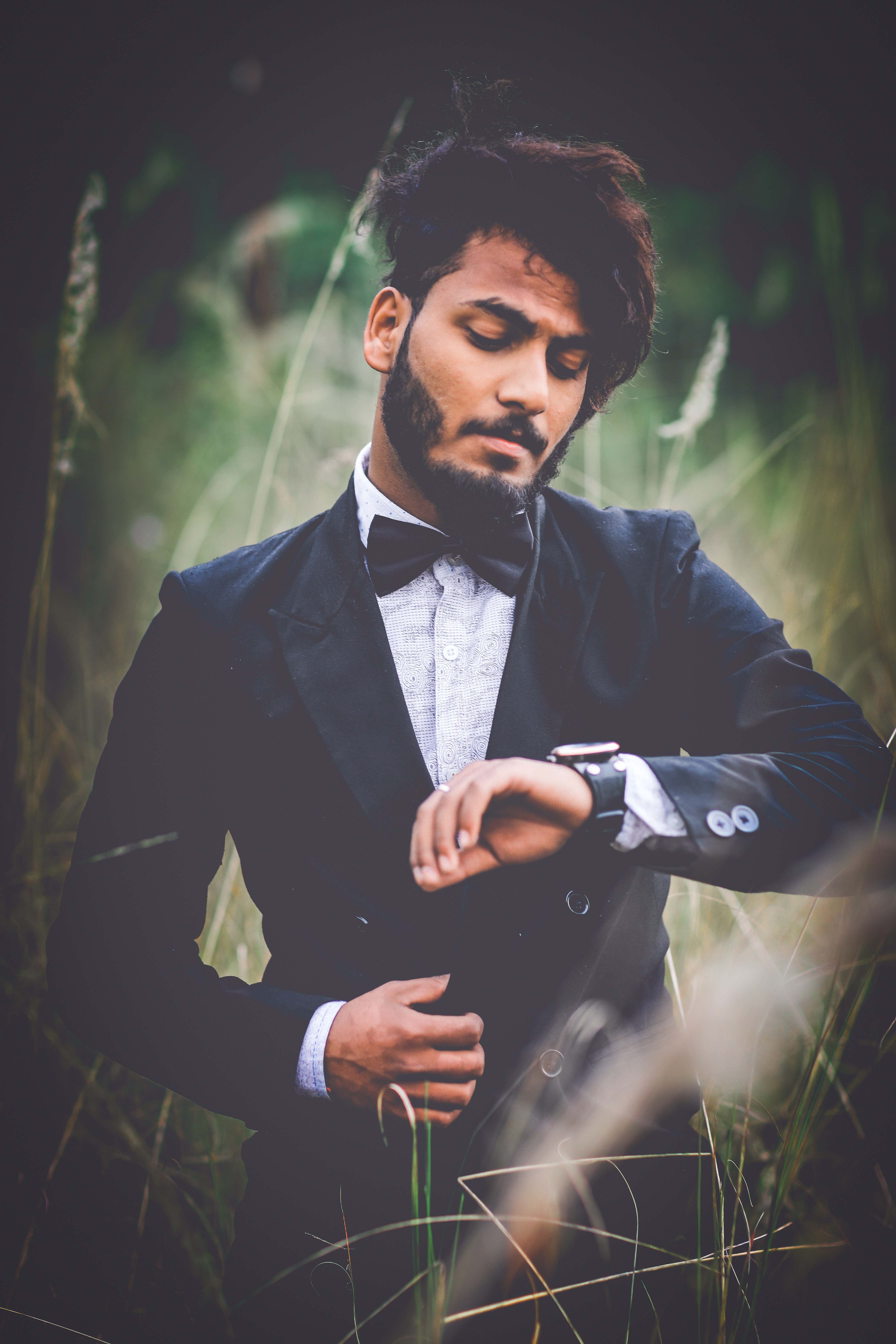 Man in tuxedo suit surrounded by grass photo