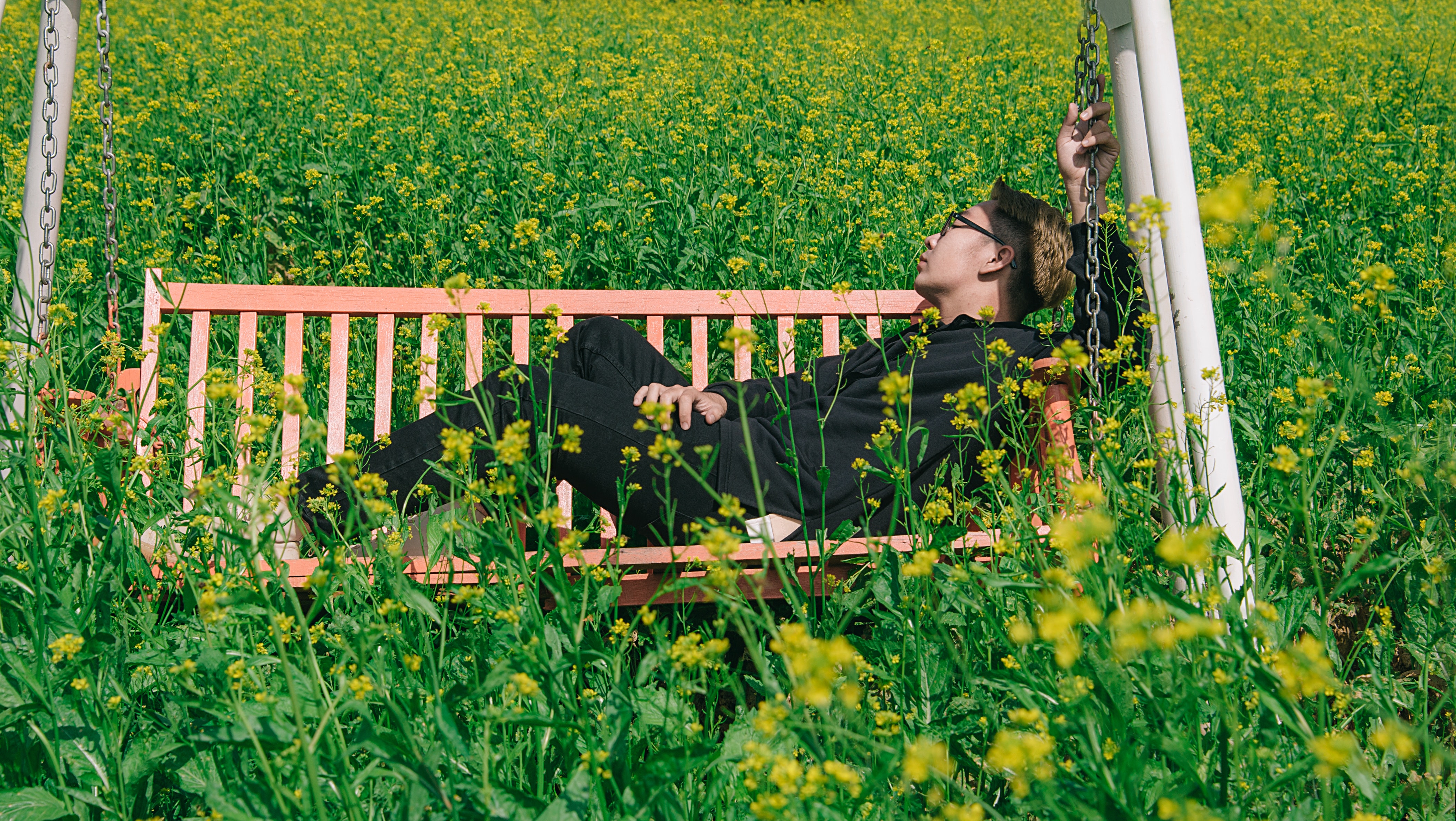Man in white and brown canopy swing surrounded with yellow petal flower photo