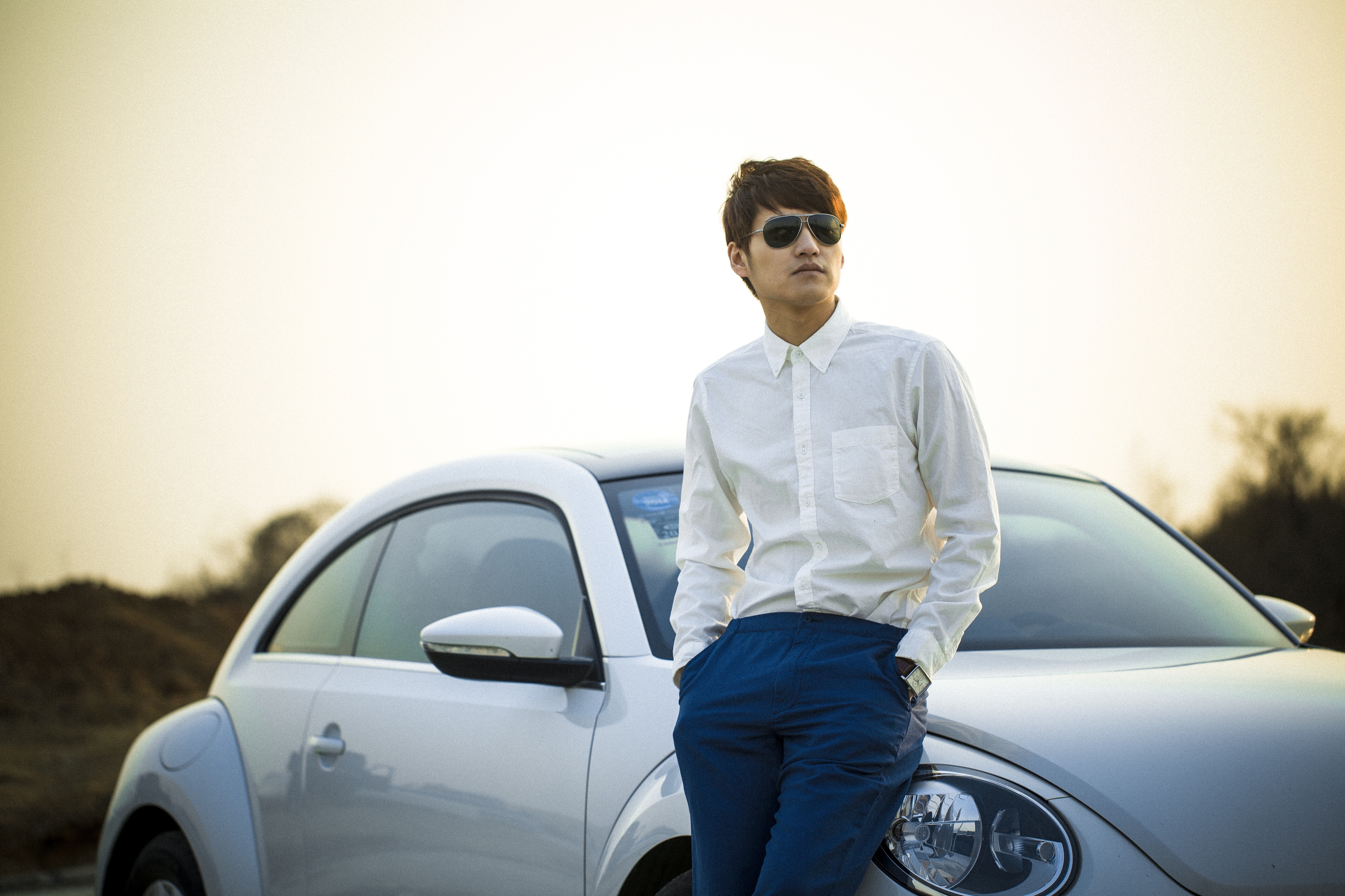 Man in white button down shirt leaning on silver beetle car photo