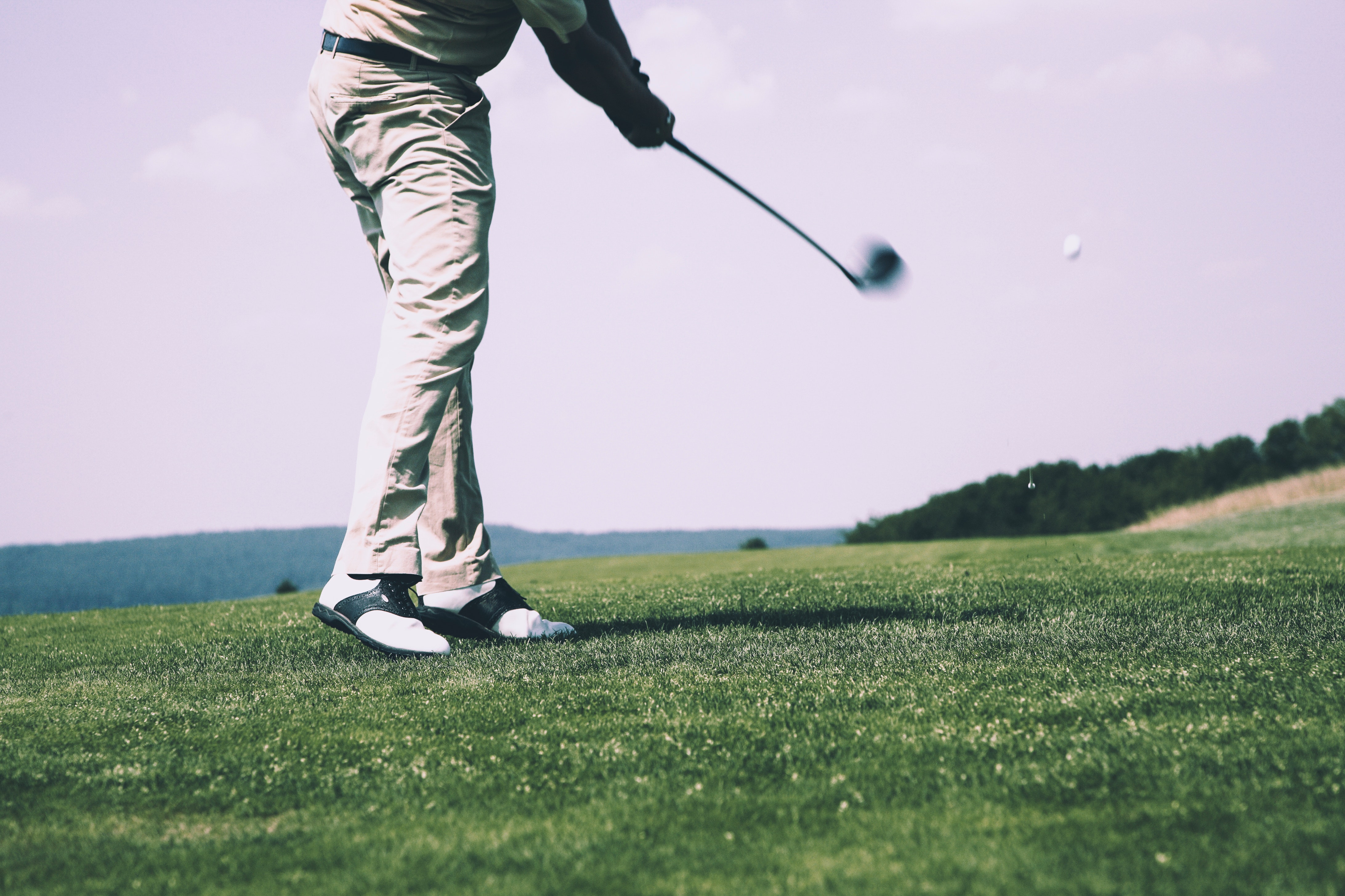 Man in white denim pants and black sandals playing golf during daytime photo