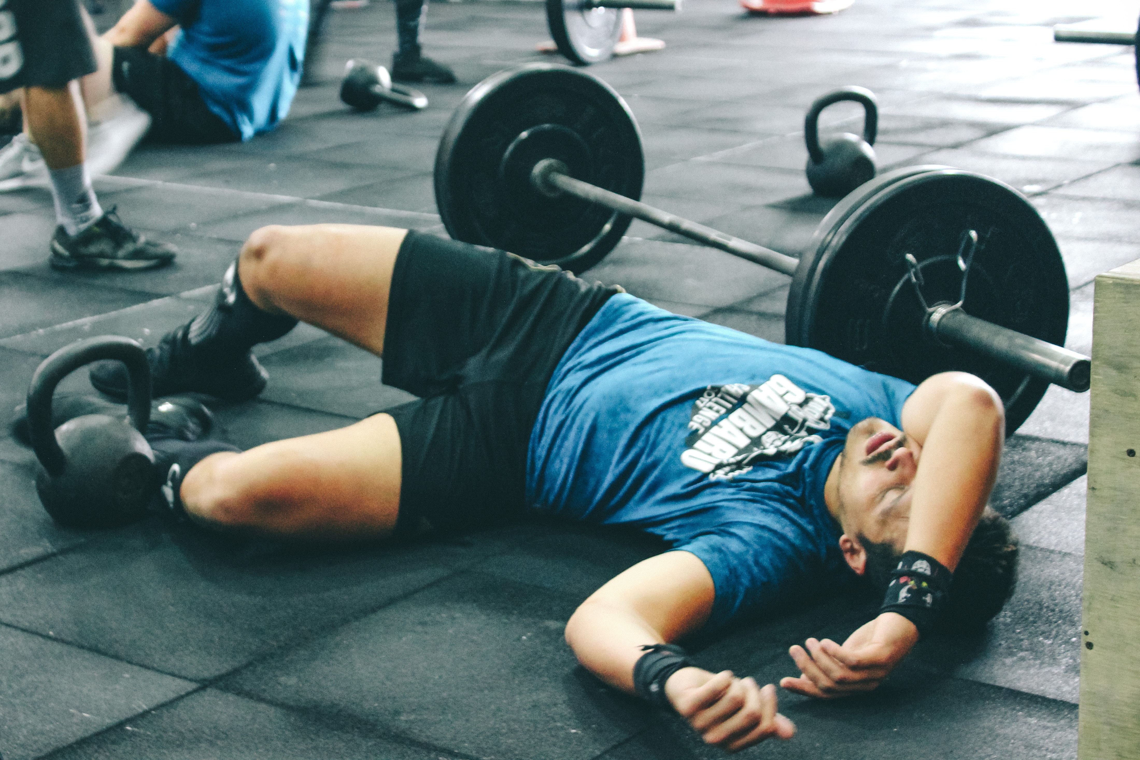 Man lying on rubber mat near barbell inside the gym photo