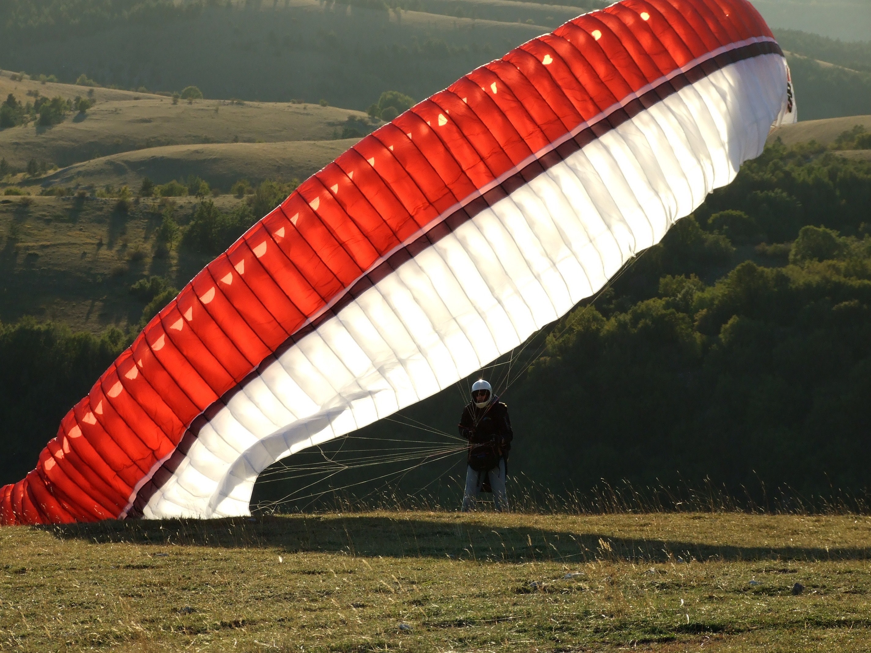Man on the ground with a red black and white parachute photo