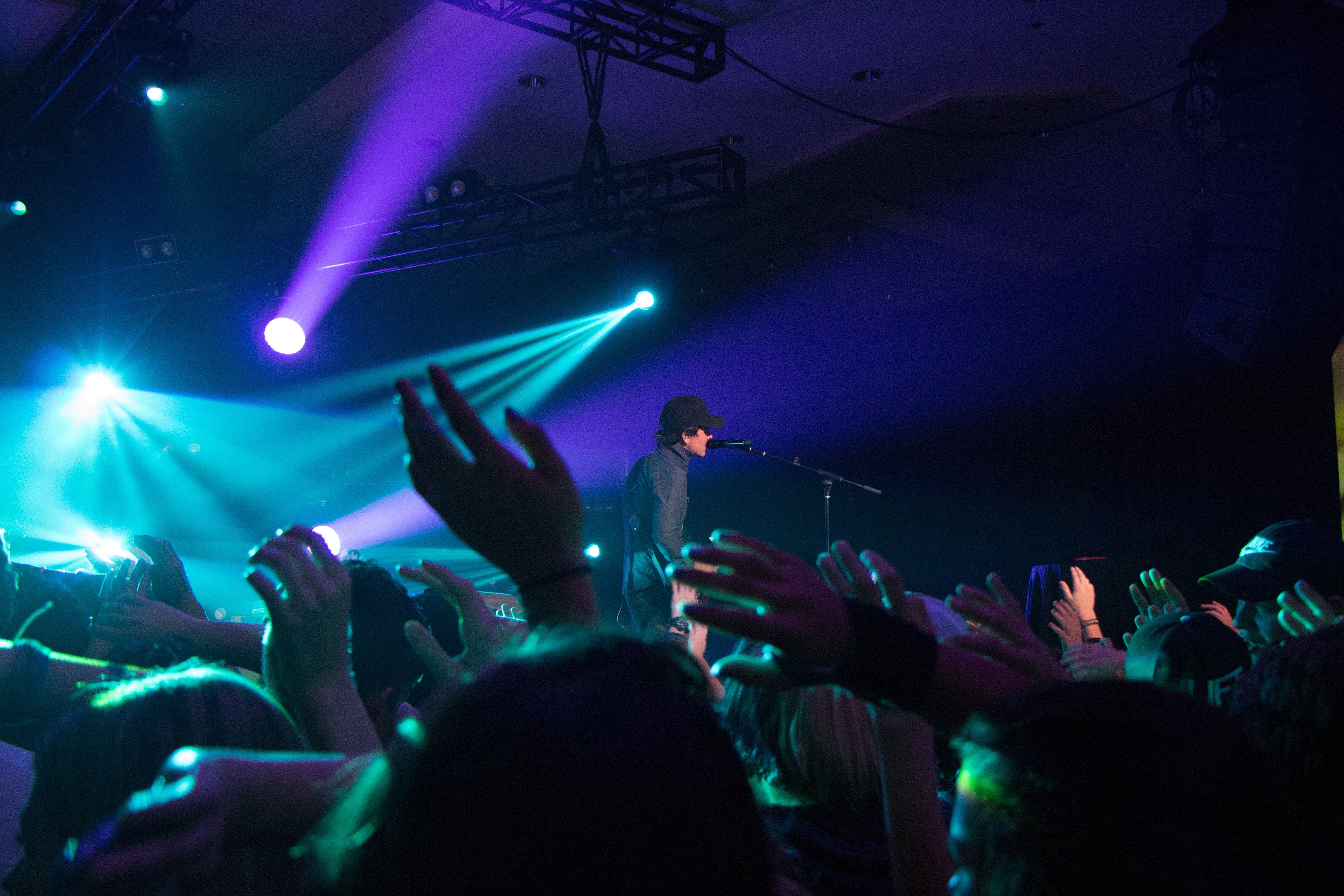 Man singing on stage with stage lights near crowd photo