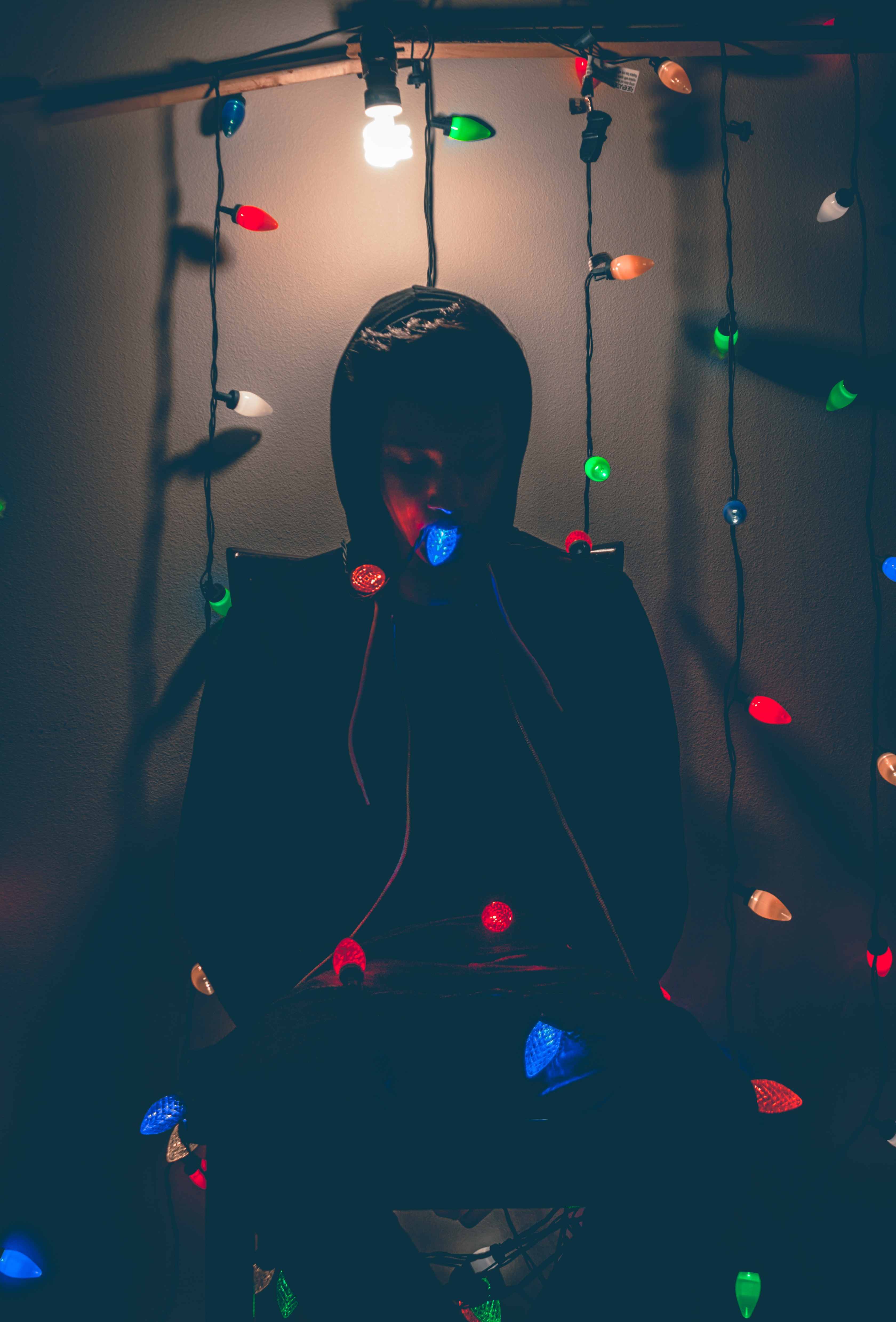Man sitting on chair with multi-colored string lights photo