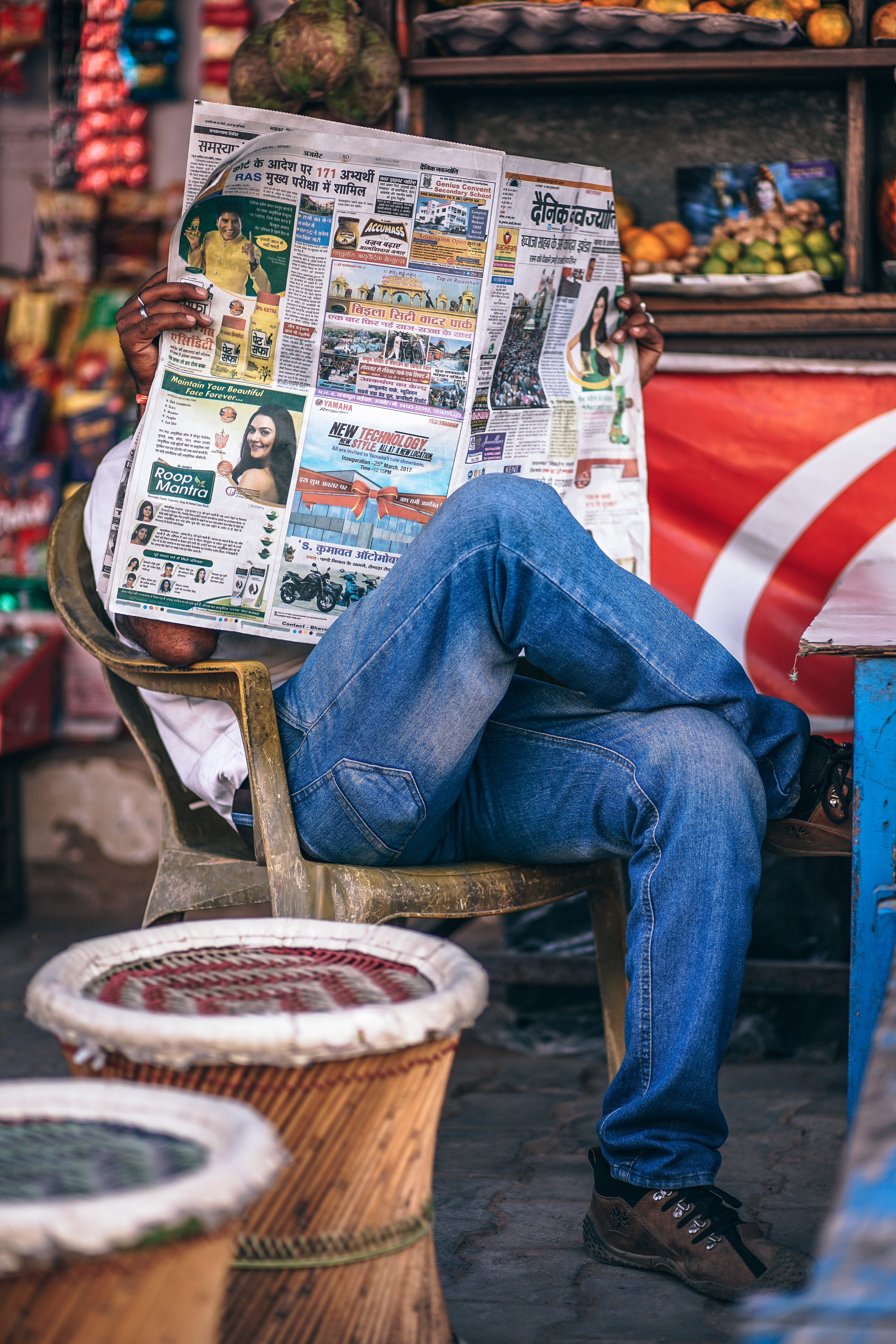 Man sitting on plastic armchair reading newspaper photo
