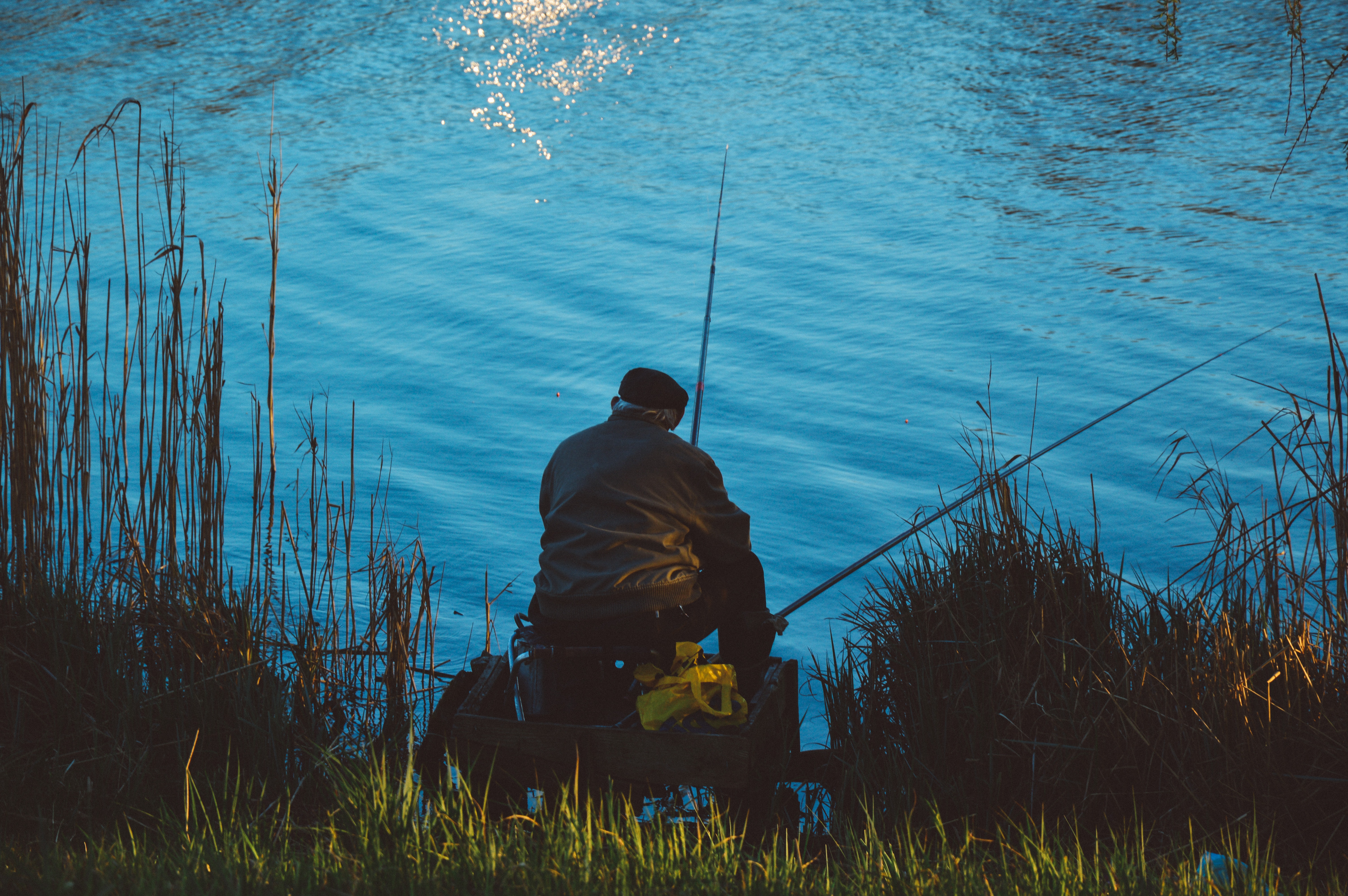 Man sitting on the chair while doing fishing near body of water photo