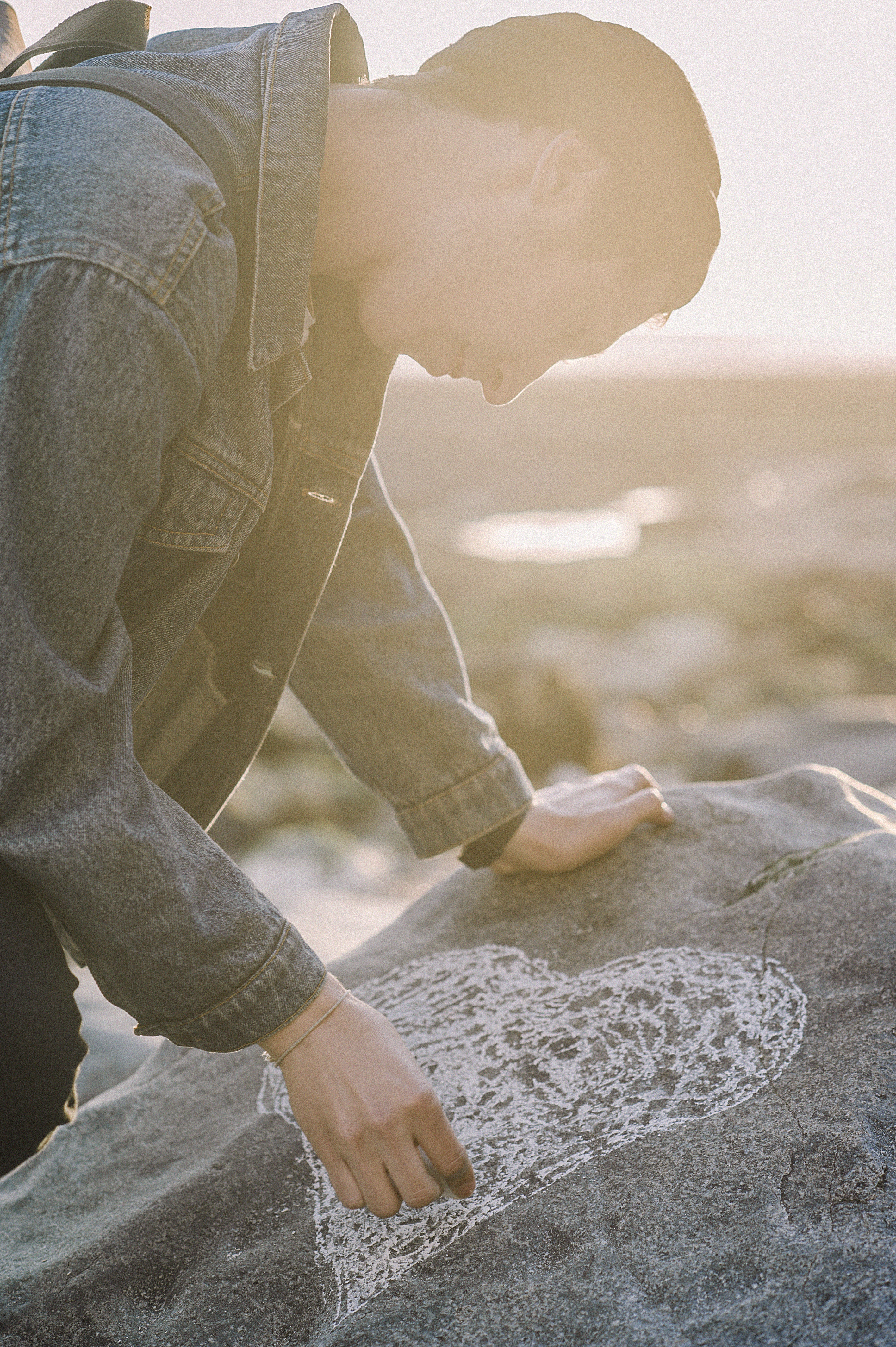 Man sketching heart on a gray rock photo