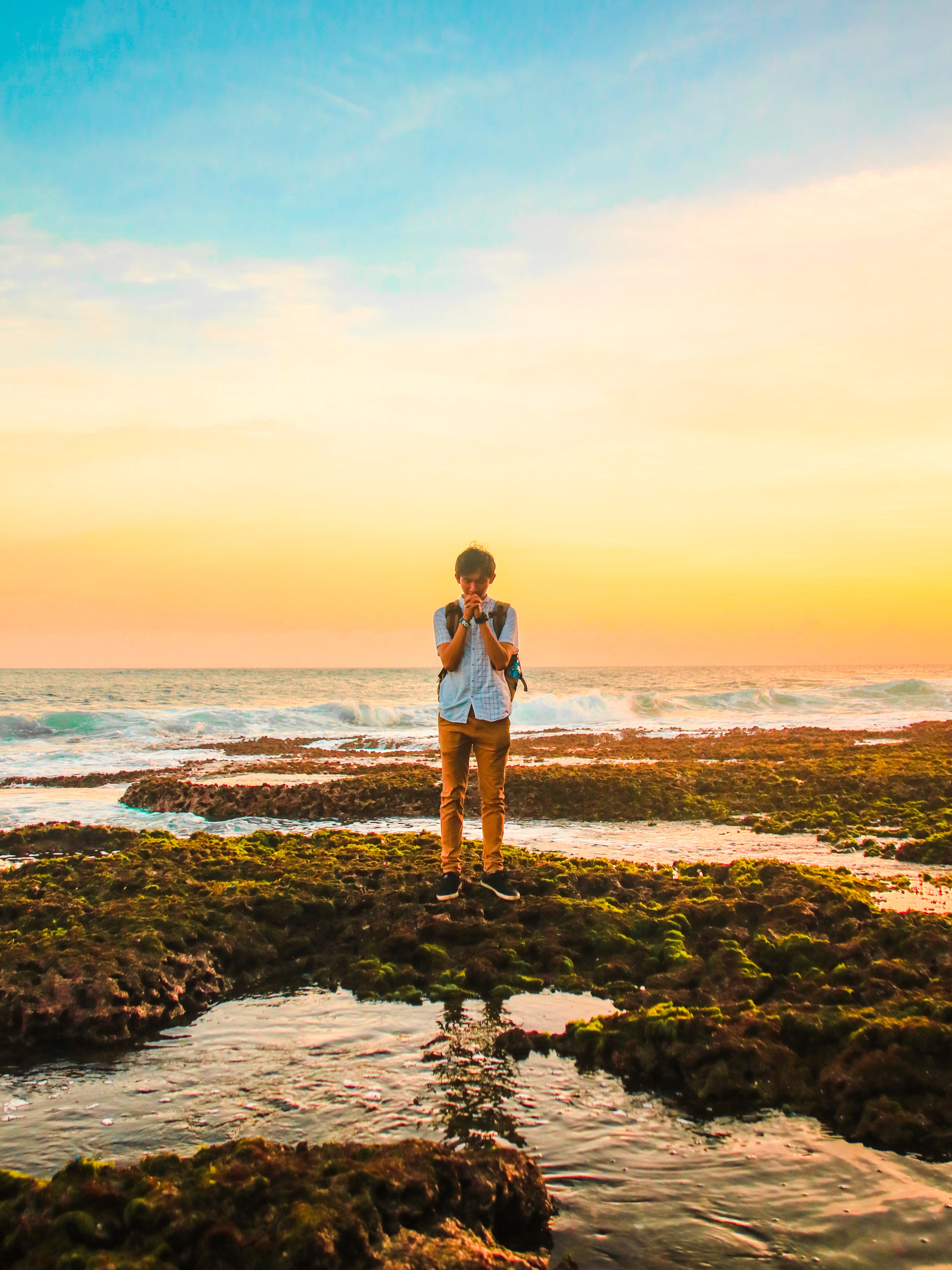 Man standing on rocks near beach during golden hour photo