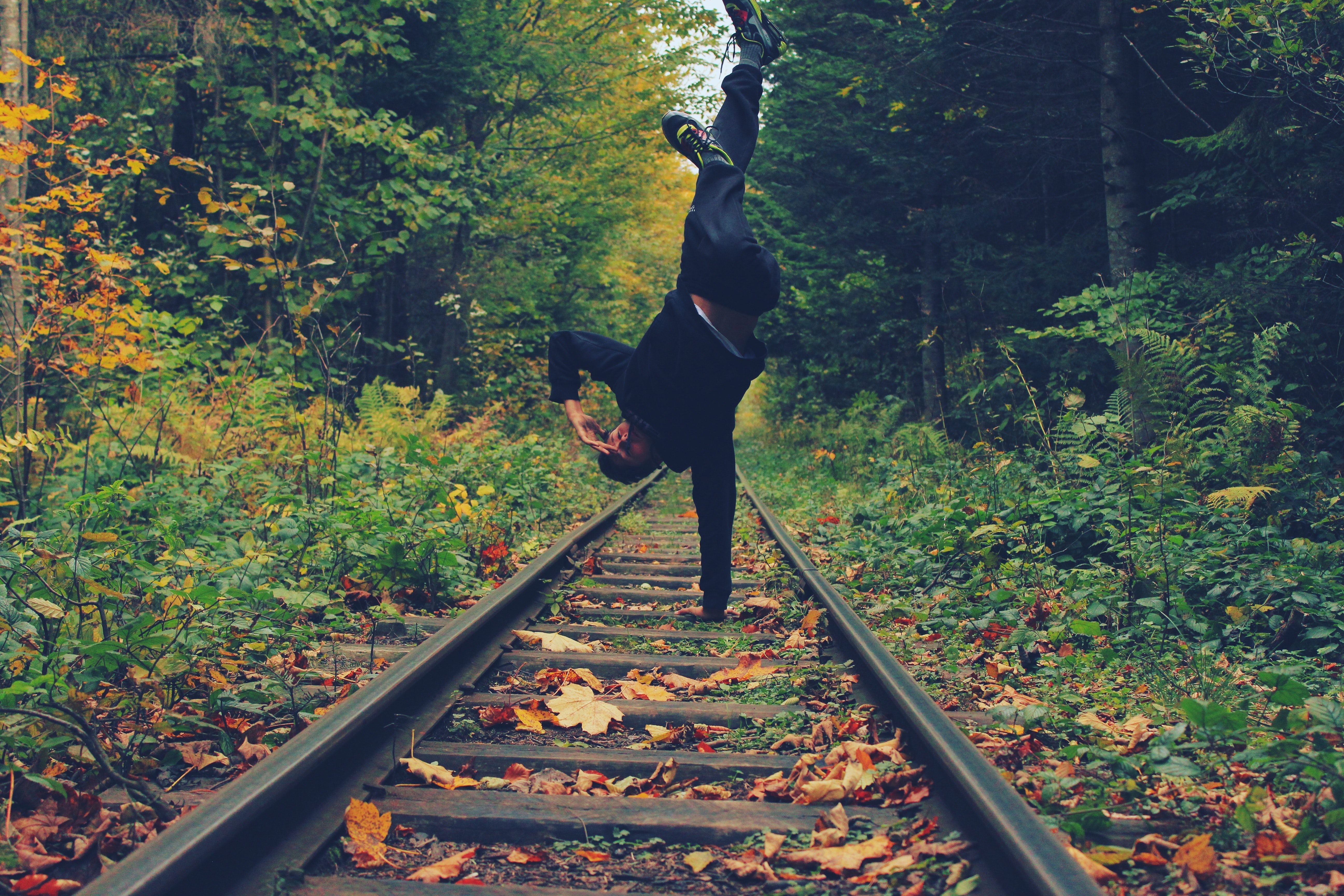 Man standing with his right hand on the train rails in middle of forest photo