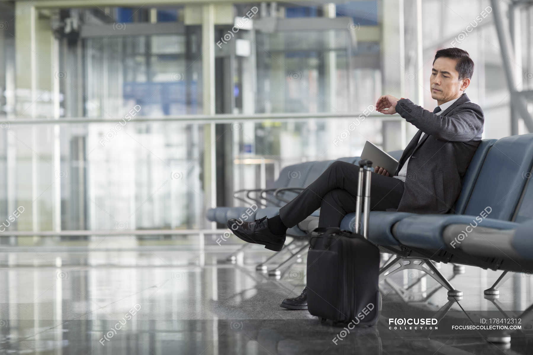 Asian man waiting in airport and looking at wristwatch — Stock Photo ...
