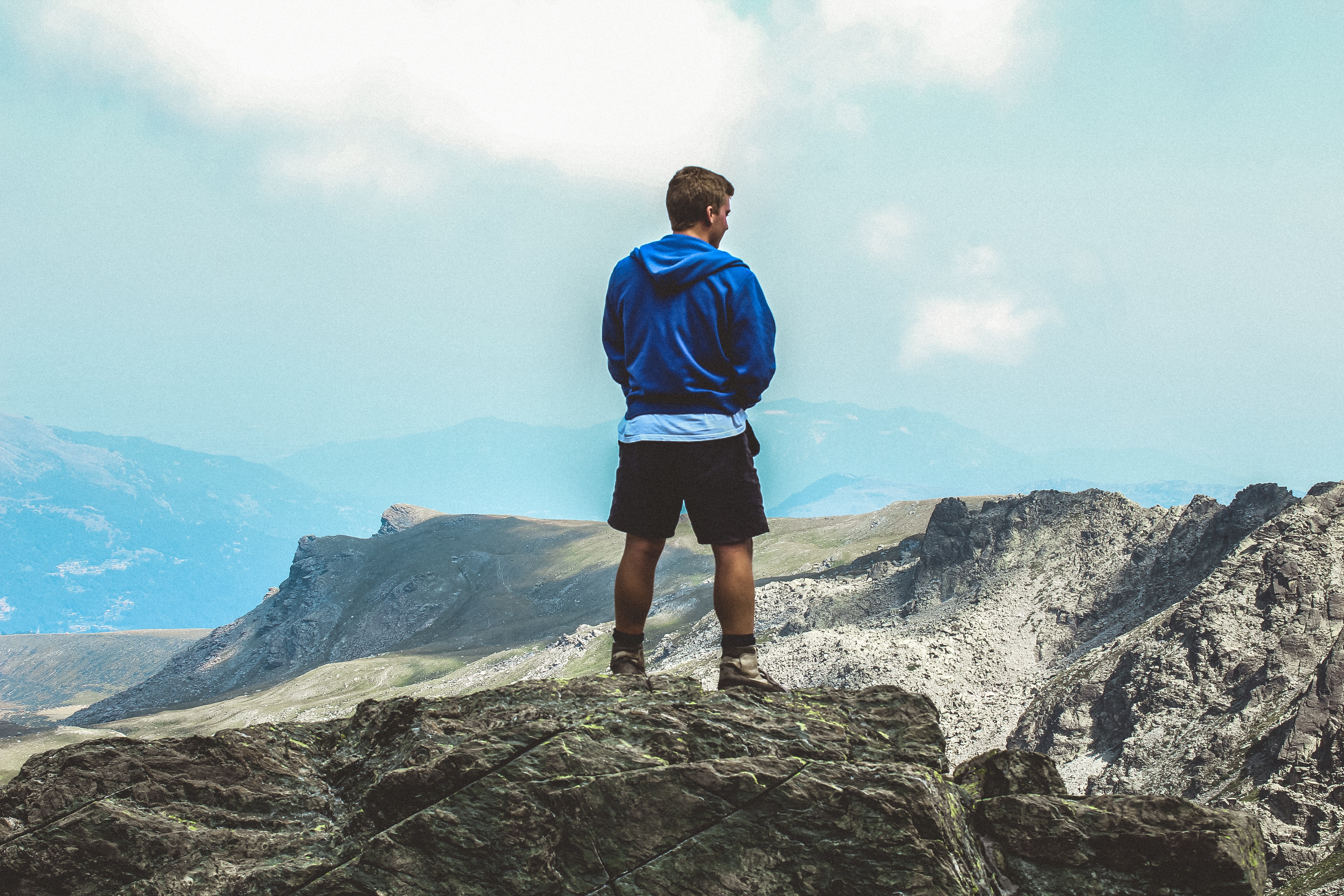 Man wearing blue hoodie standing on top of mountain photo
