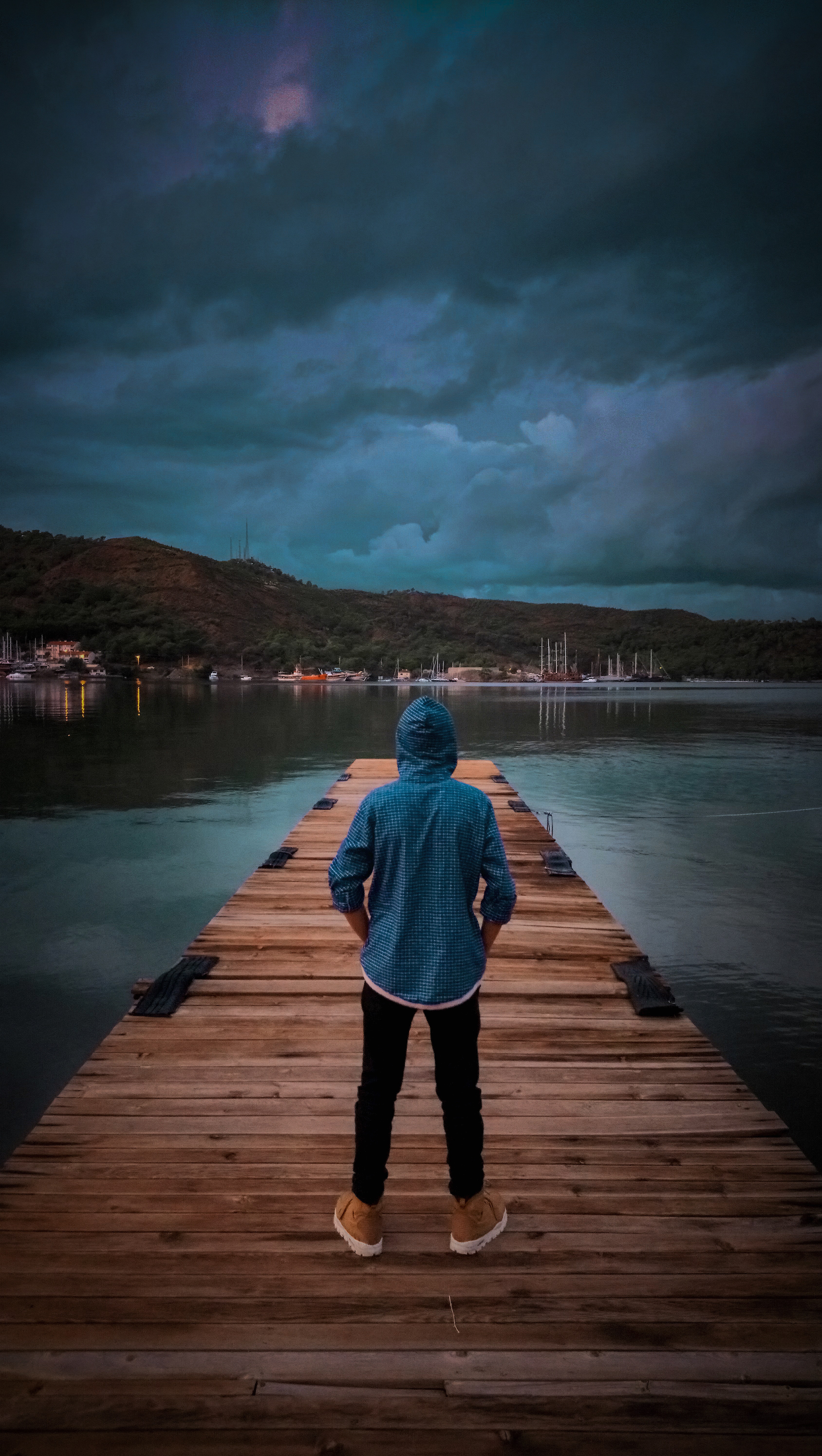Man wearing blue hoodie standing on wooden dock photo