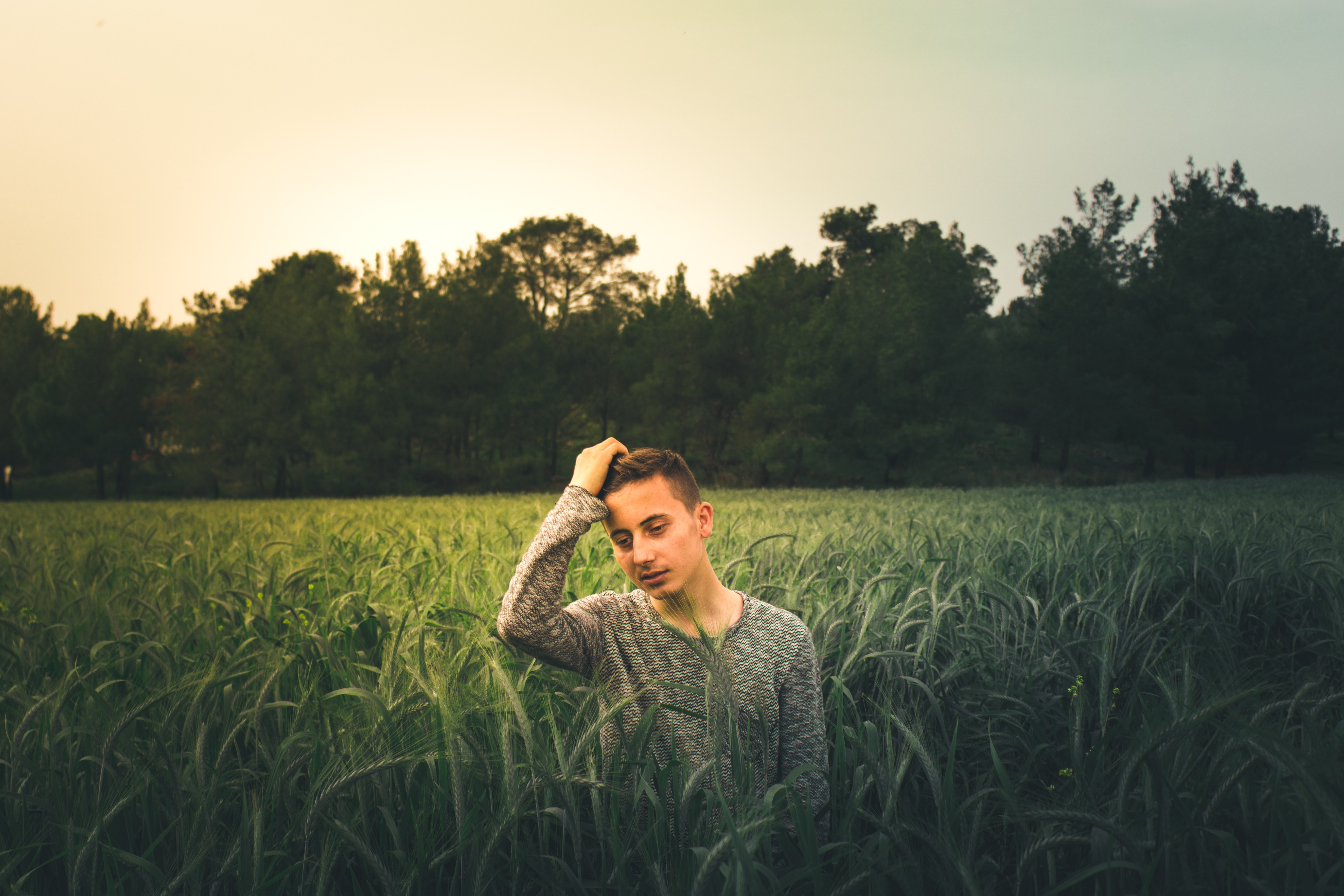 Man wearing gray sweatshirt standing on grass field photo