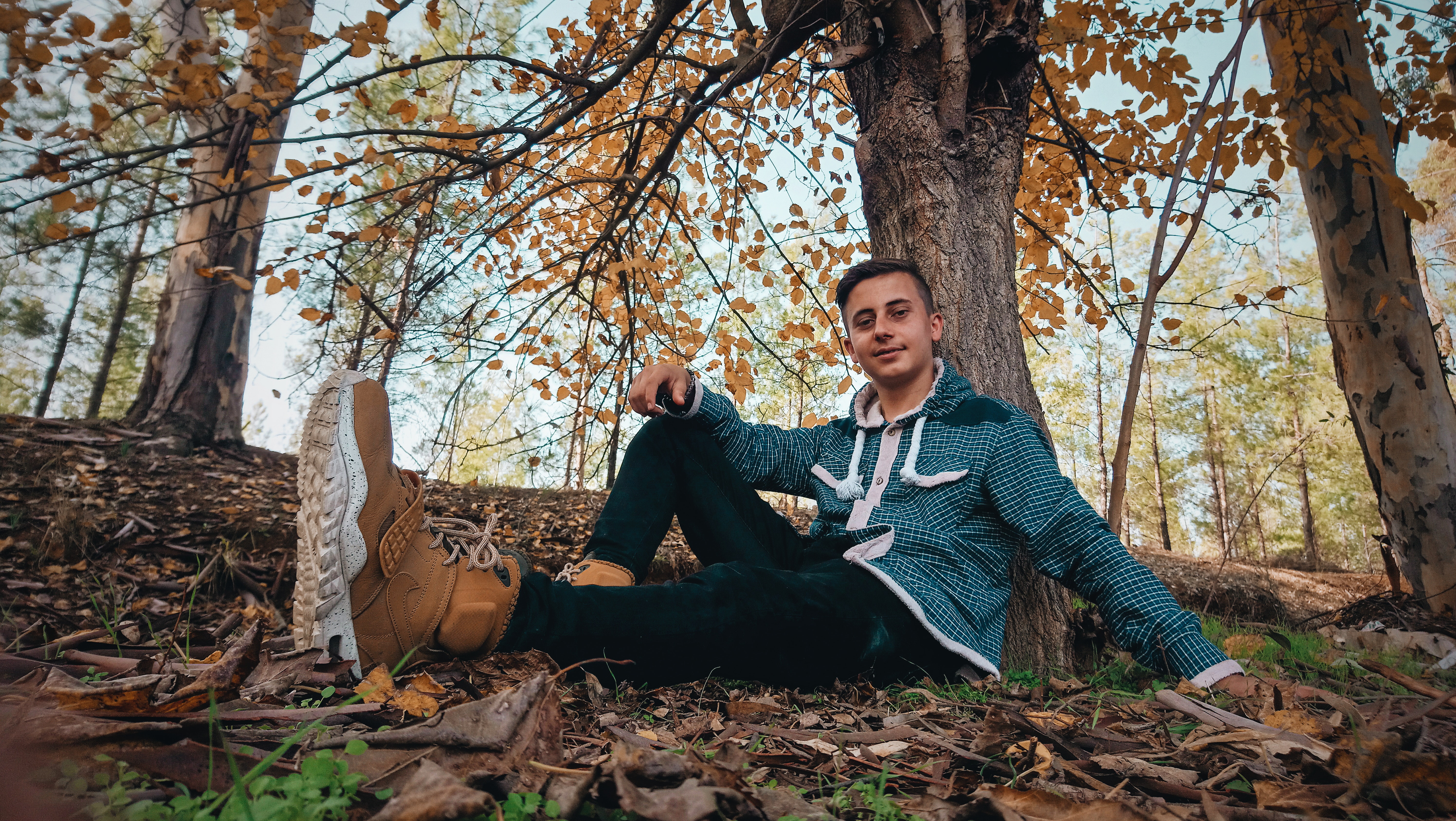 Man wearing green jacket sitting on ground near tree photo