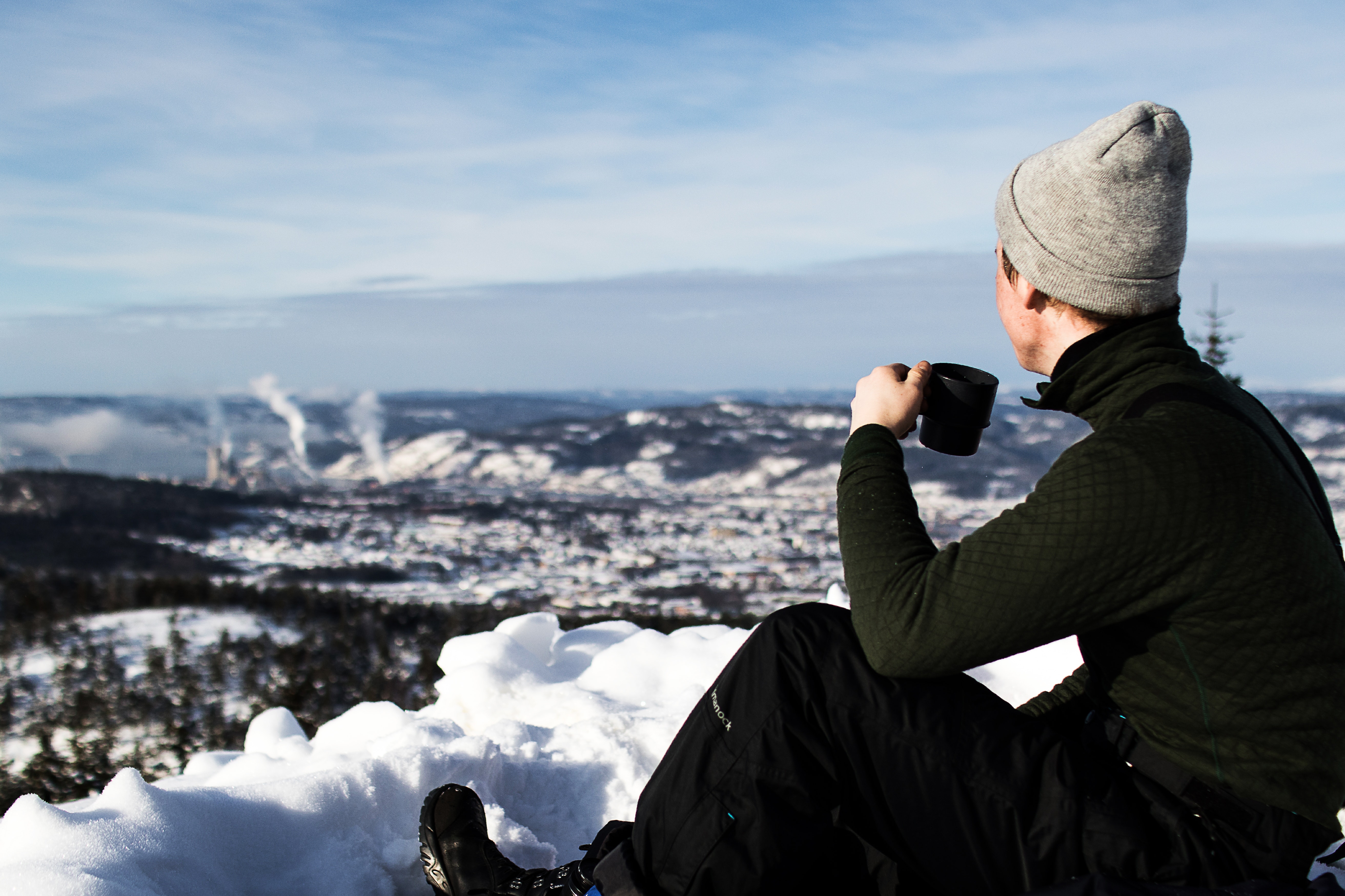 Man wearing jacket and holding cup sitting on the snow photo