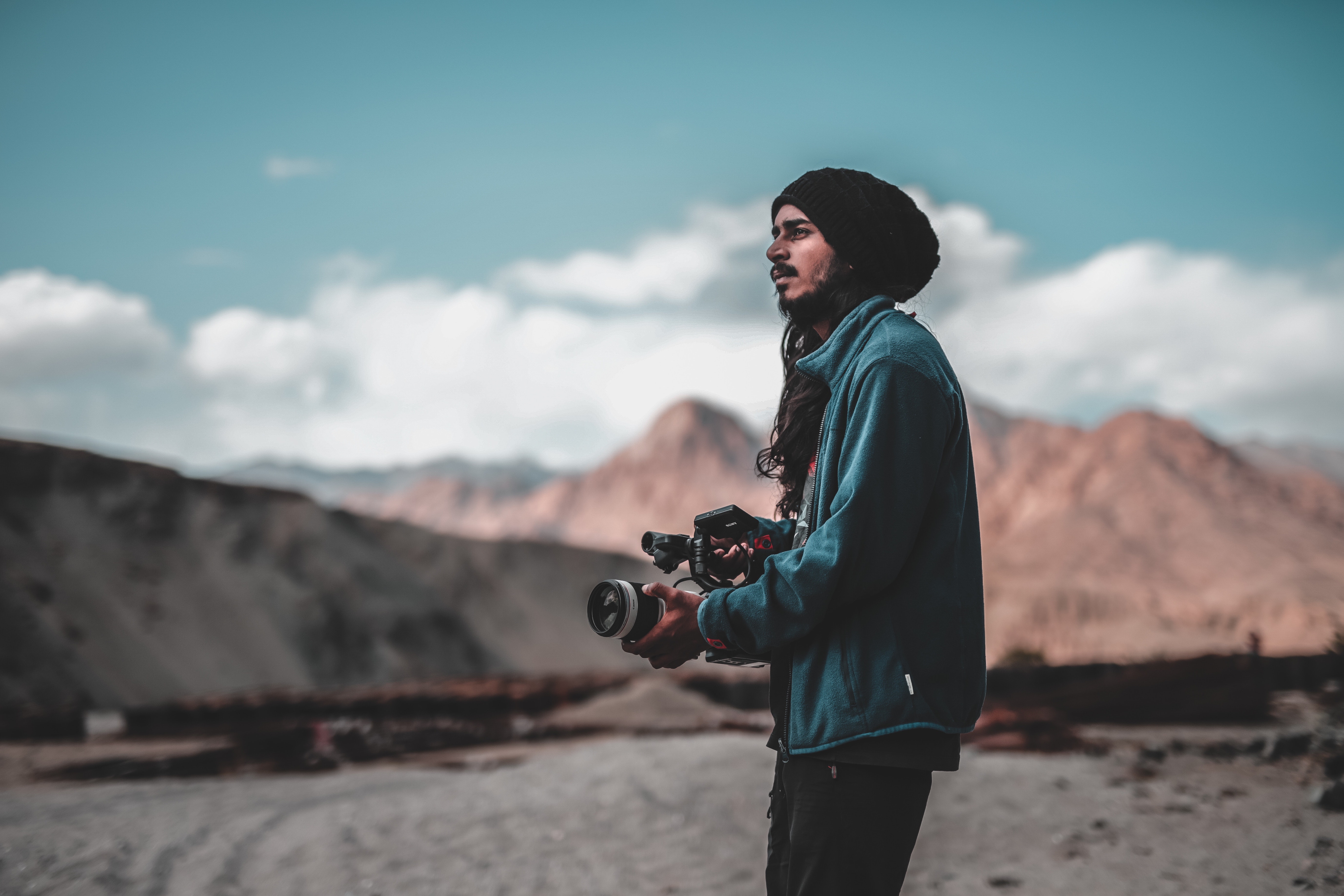 Man wearing jacket holding dslr camera on desert photo