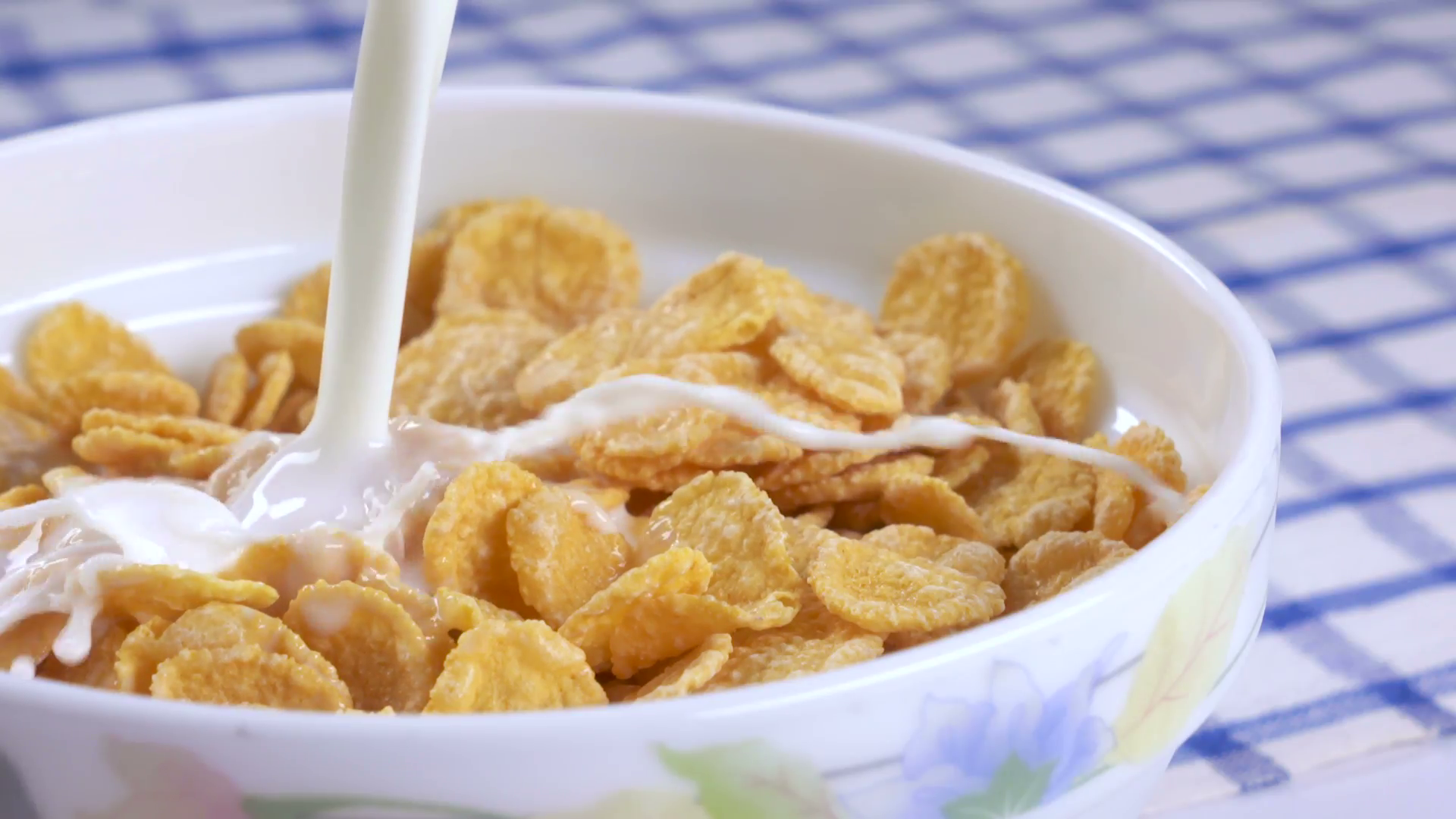 Breakfast cereal pouring milk with splashes into bowl of golden corn ...