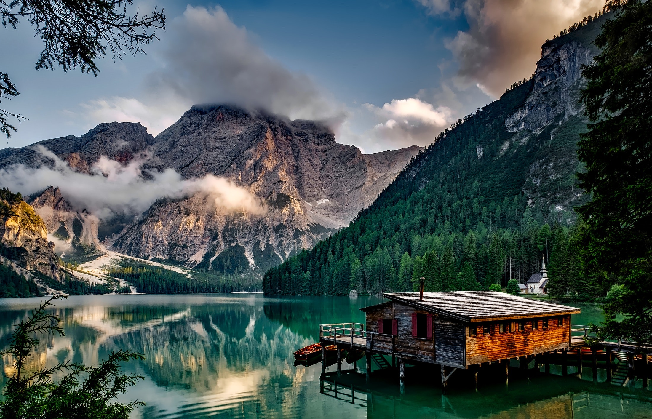 Mirror lake reflecting wooden house in middle of lake overlooking mountain ranges photo