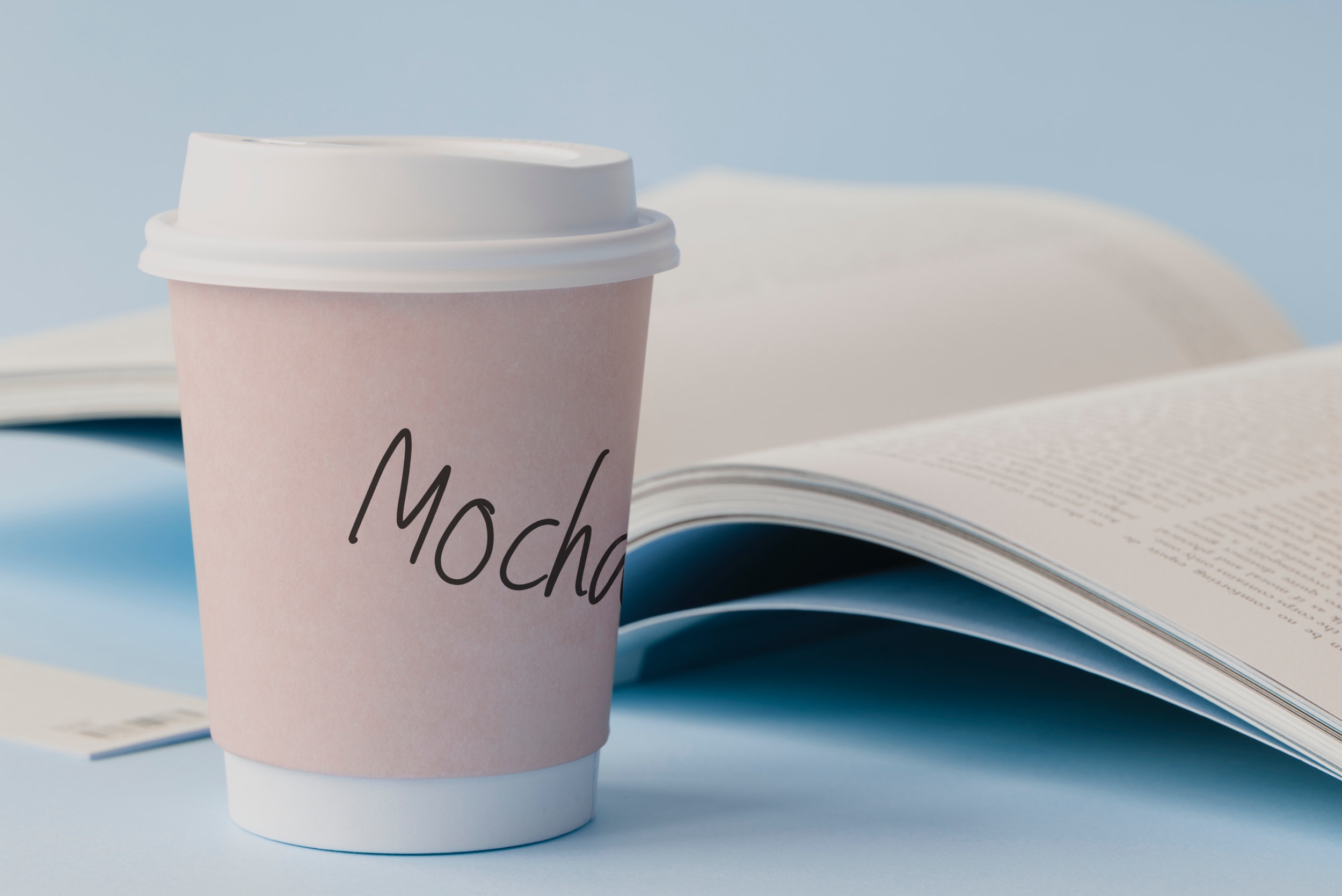 Mocha labeled white disposable coffee cup beside book photo