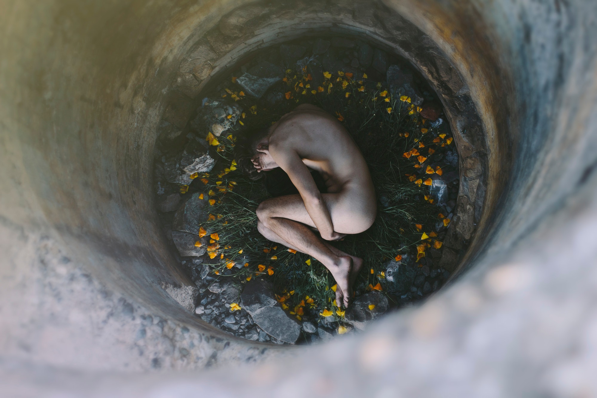 Nude person inside well laying on flowers photo