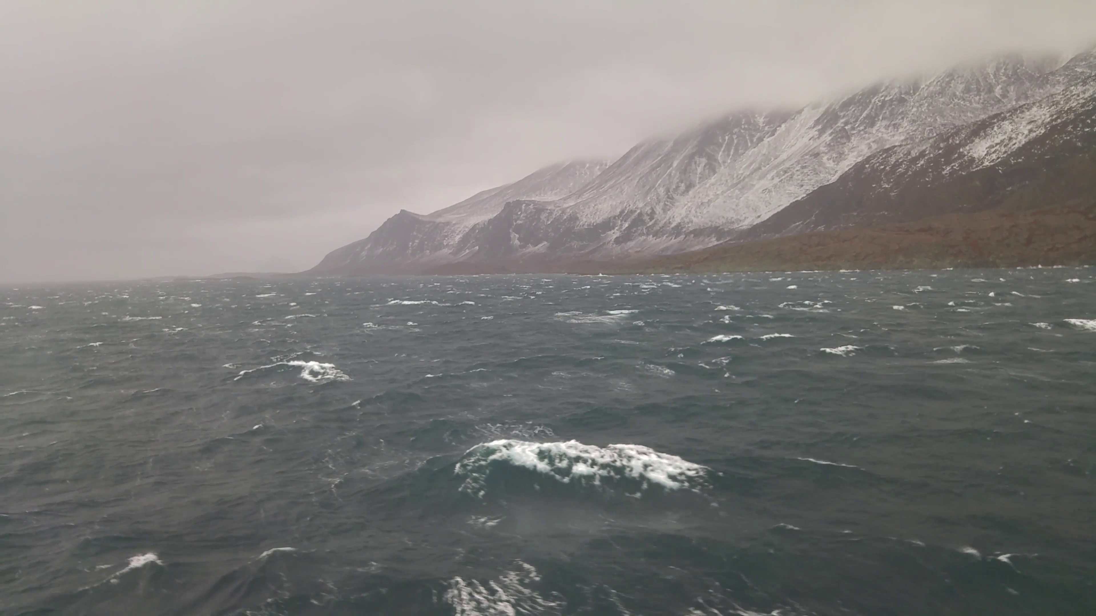 Tempest in the ocean near snowy mountains in Greenland view from a ...