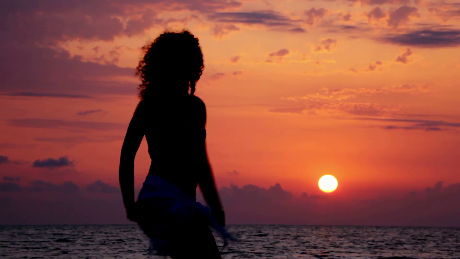 silhouette of young woman on beach, sunset sky and sea in background ...