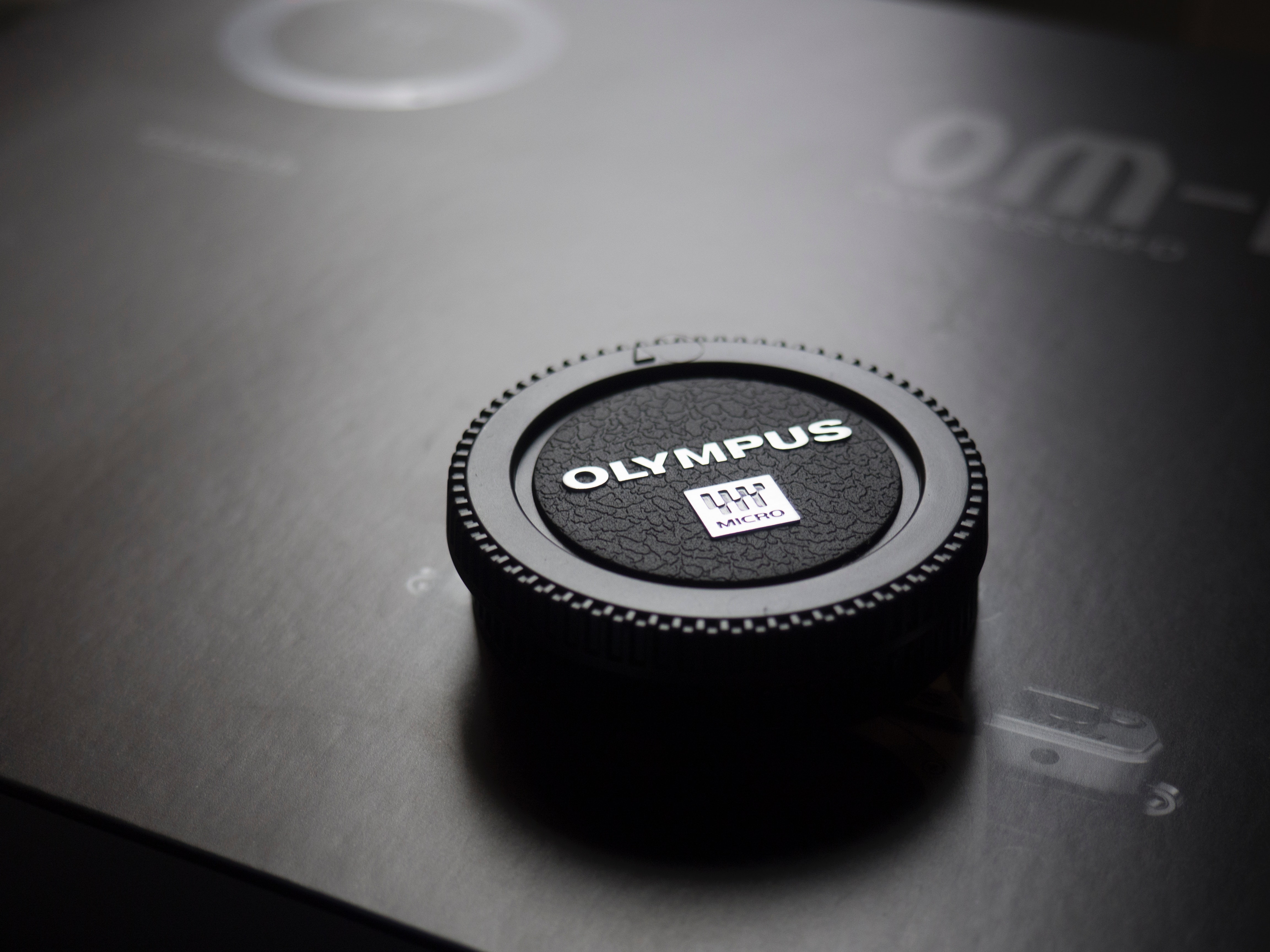 Olympus camera lens cap placed on box photo