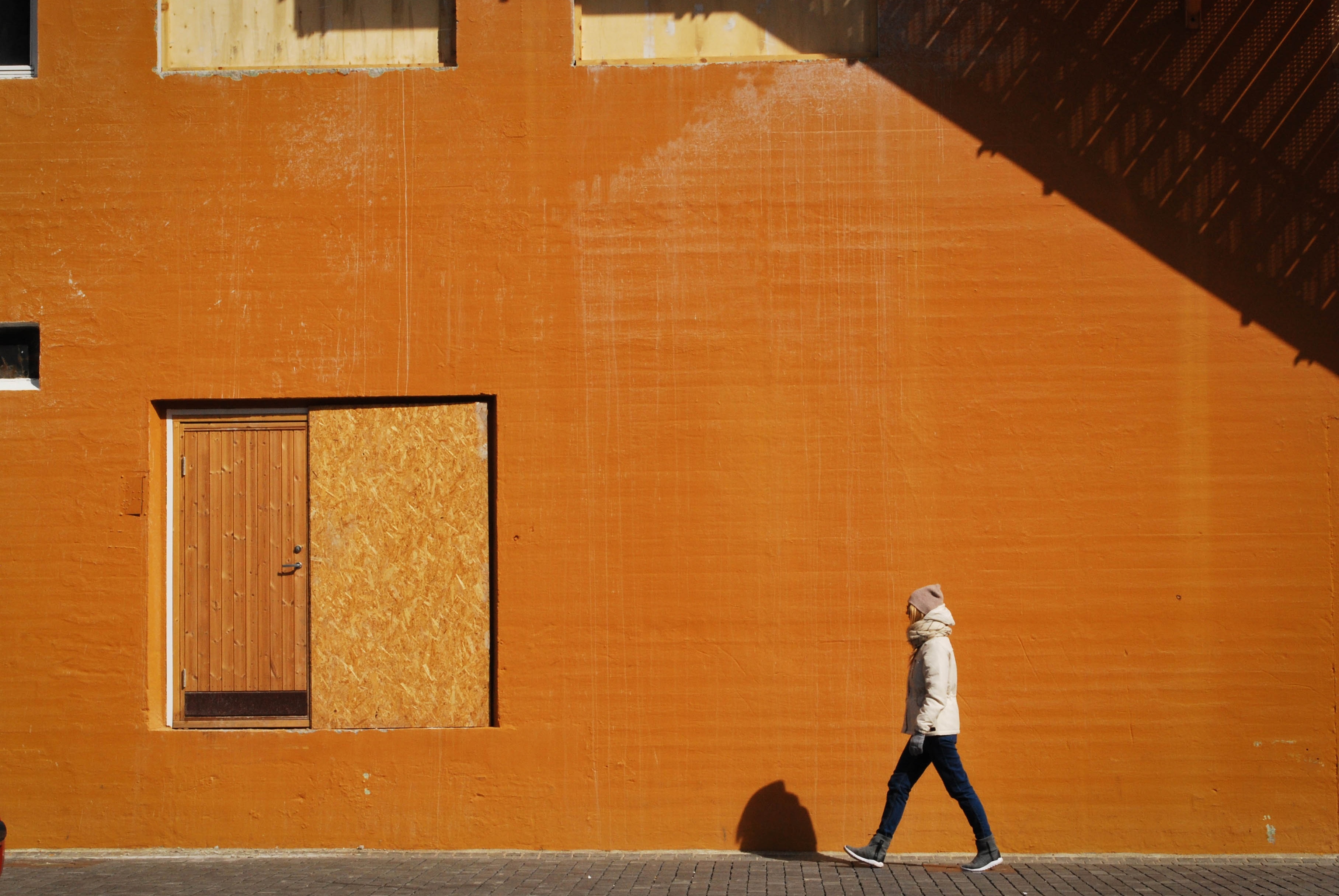 person in white jacket walking near orange concrete building free ...
