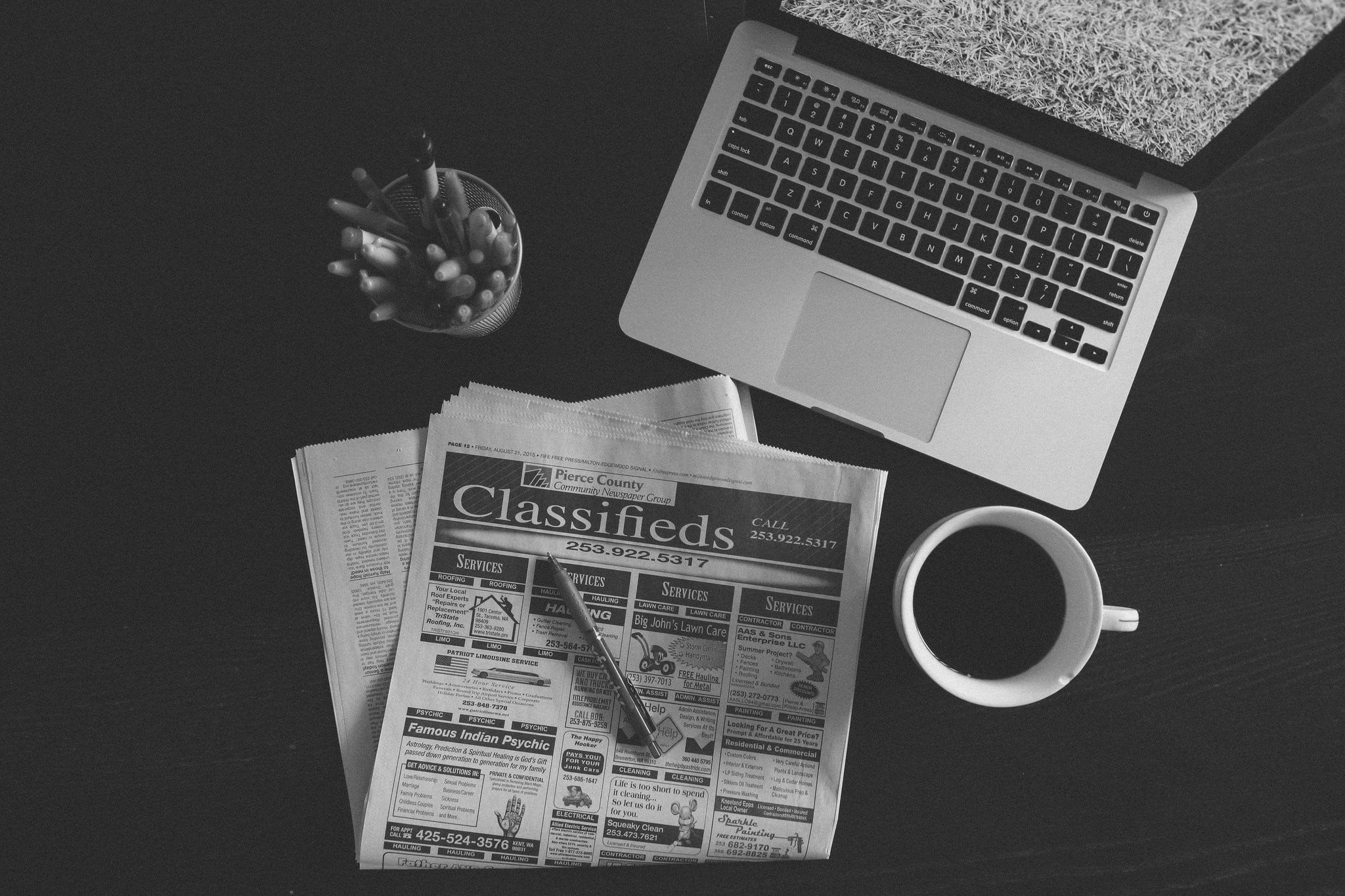 Classifieds news paper article beside coffee mug and MacBook Pro HD ...