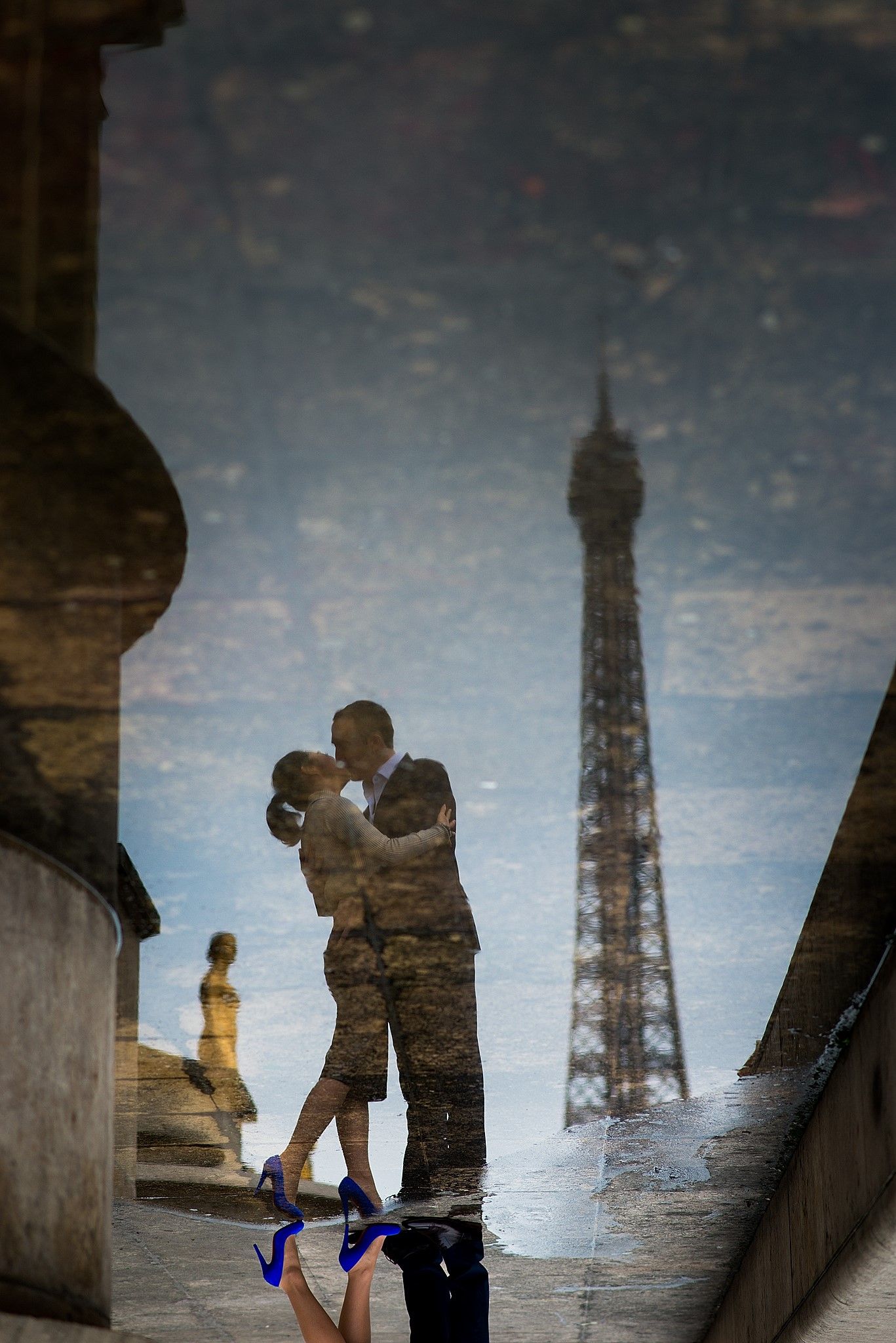 Newly engaged couple kissing in Paris. Reflection in a water puddle ...
