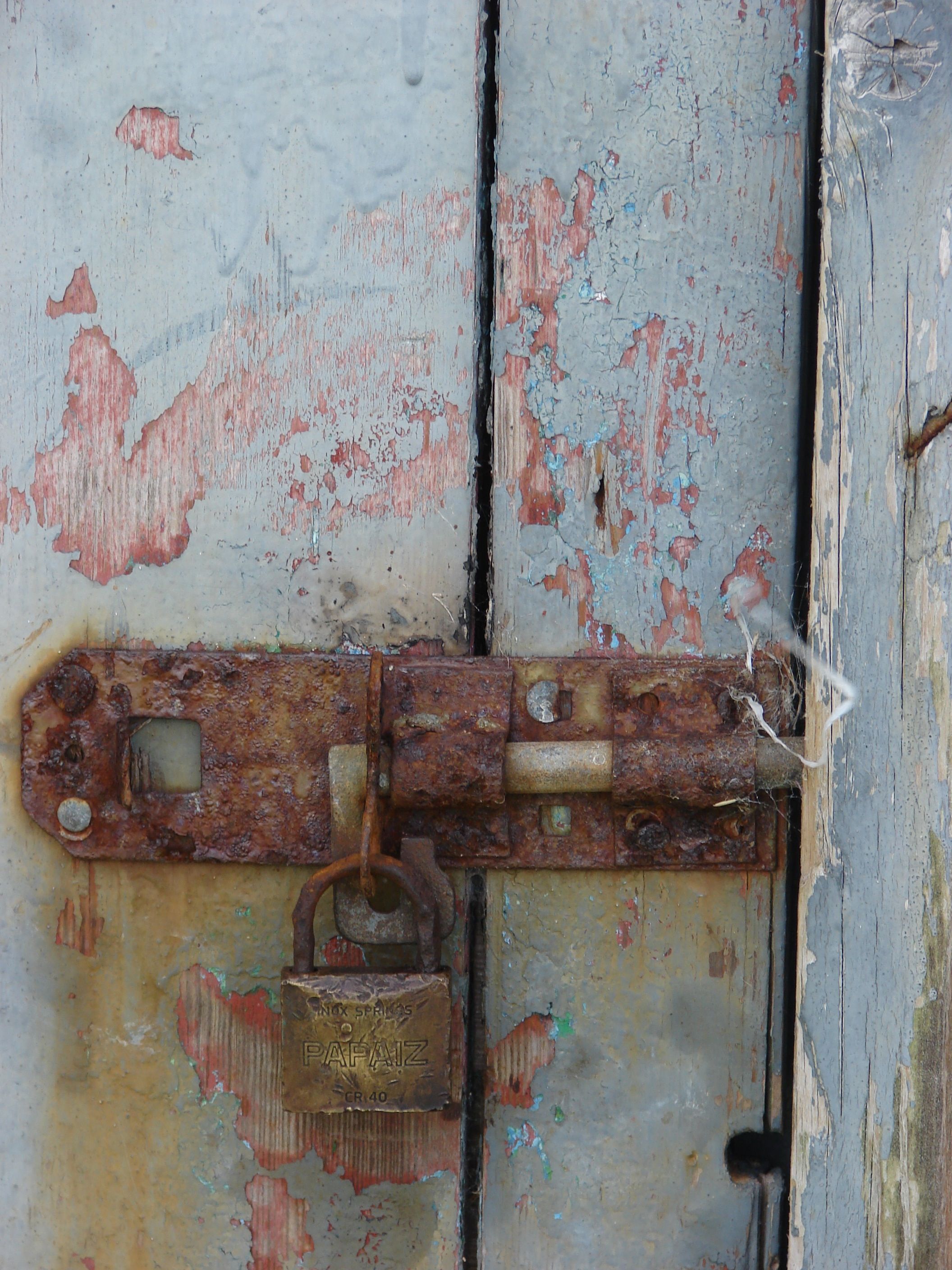 Old rusted lock on cottage door, layers of paint half peeled ...