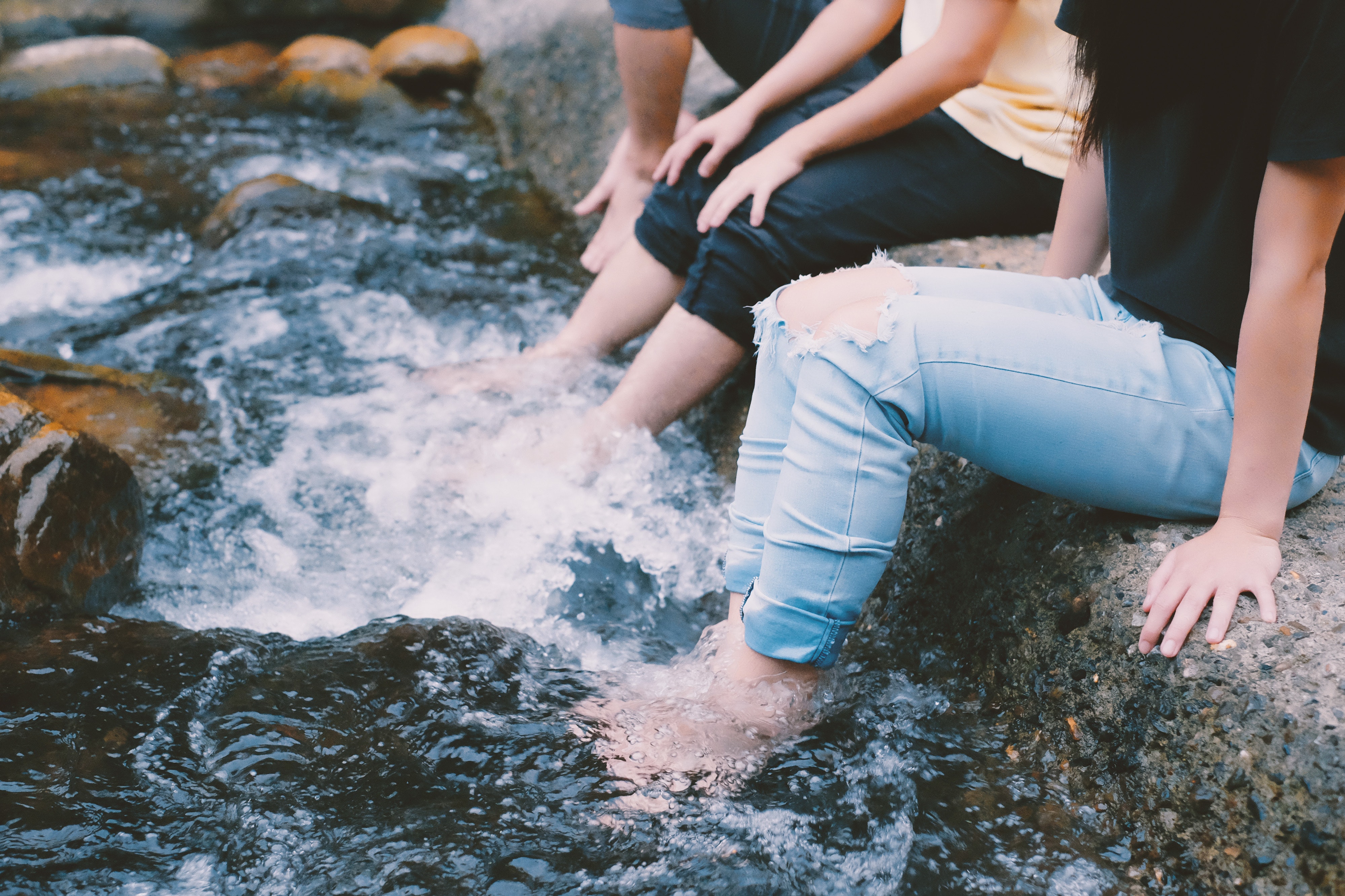 People in jeans with feet in water photo