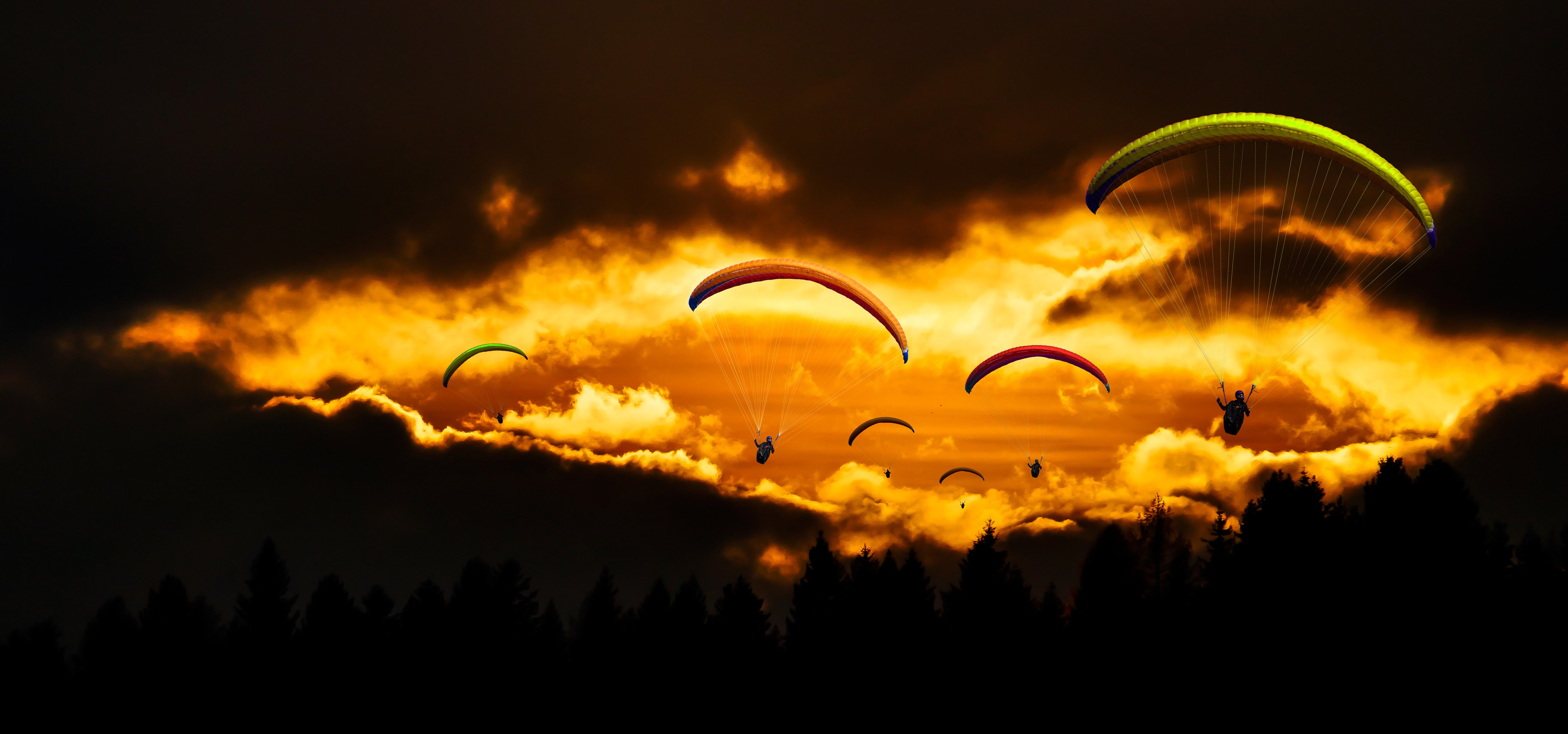 People in mid air using parachute in dusk photo