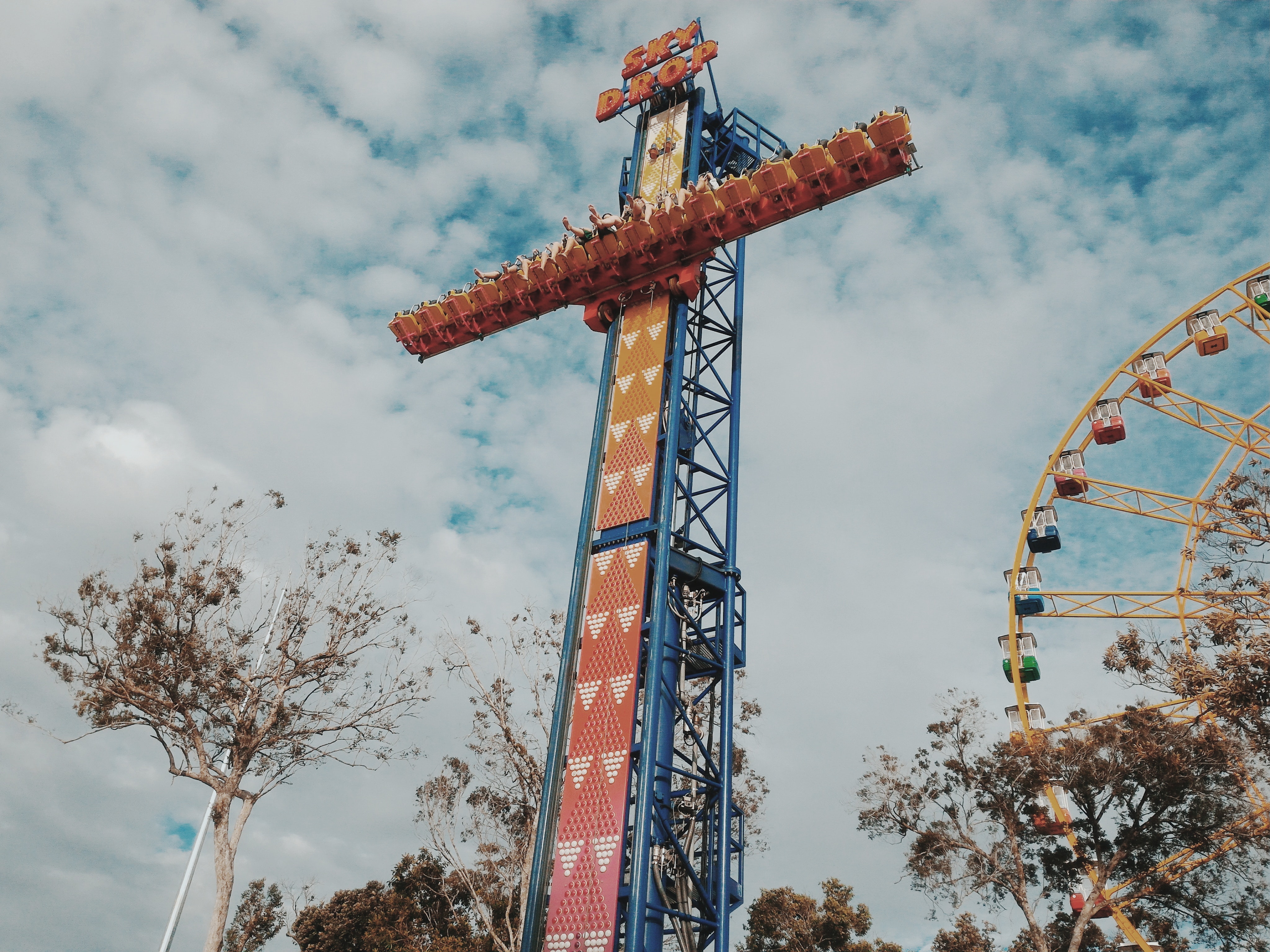 People riding on amusement park blue and orange sky drop photo