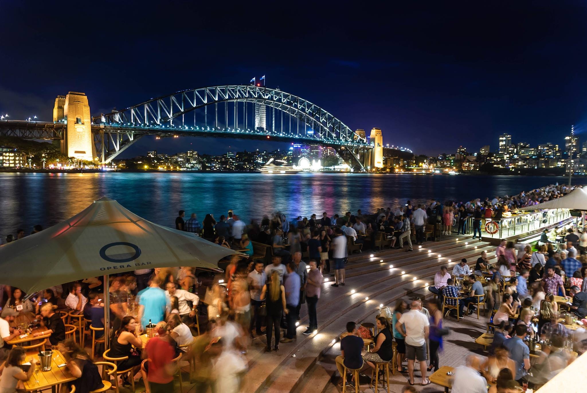 People sitting and standing near bridge during nighttime photo