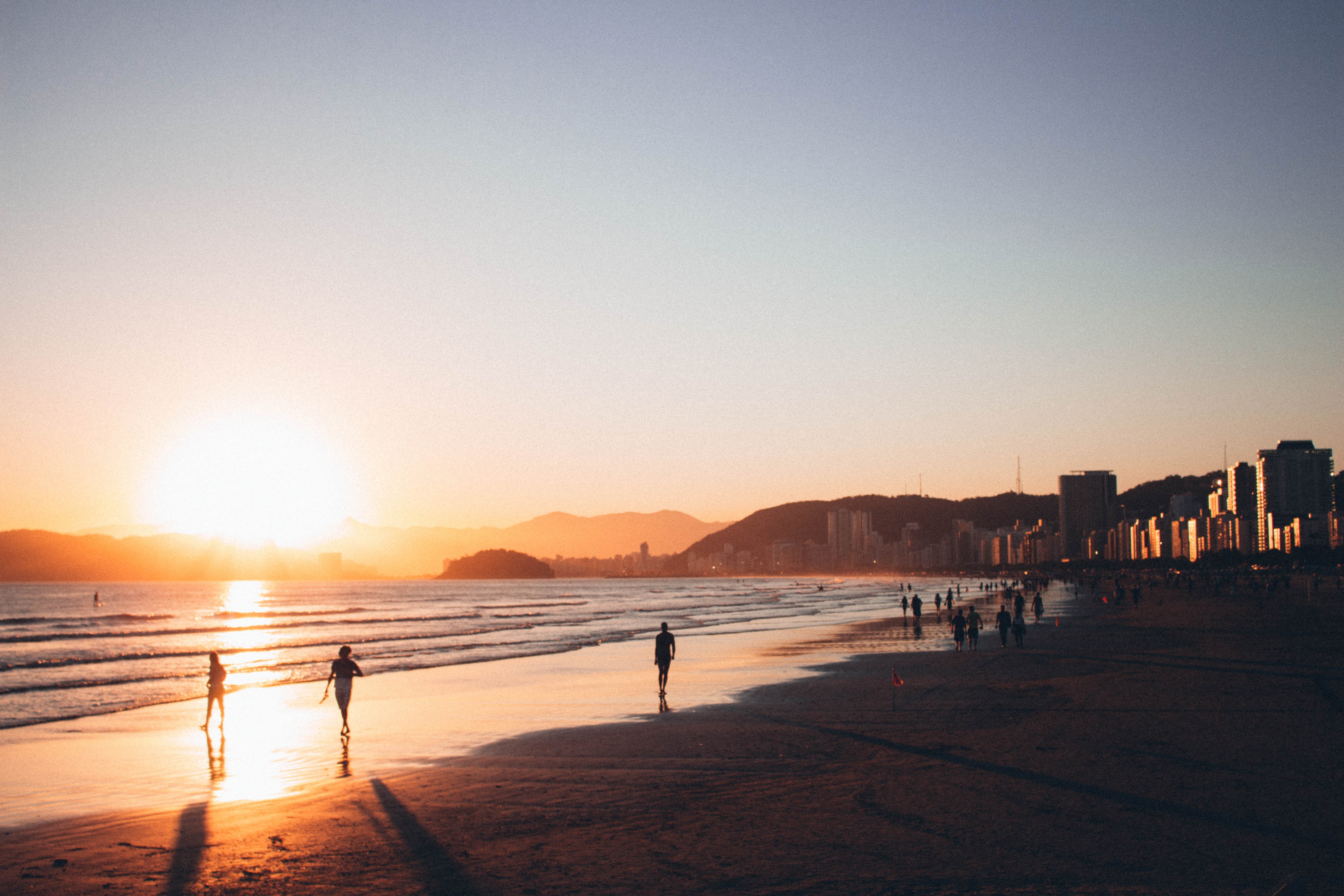 People walking on seashore during golden hour photo