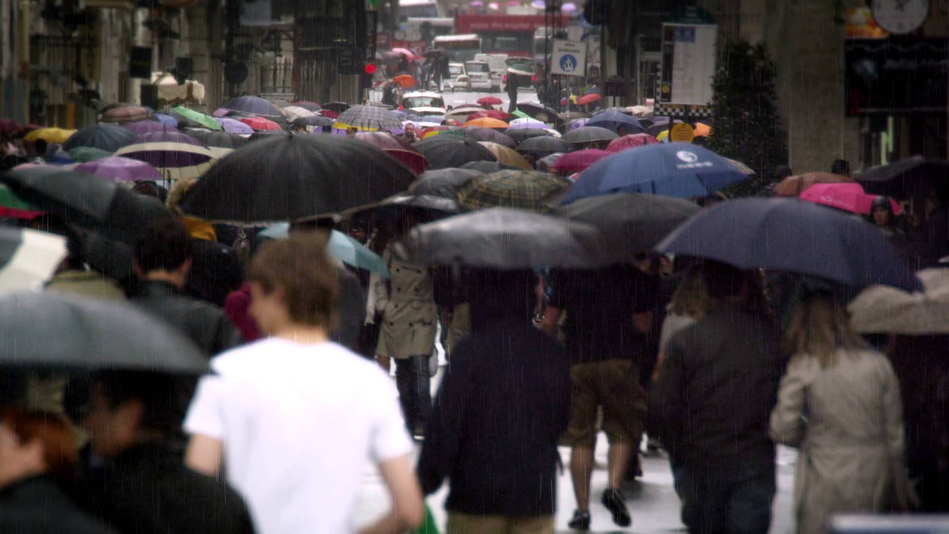 Slow motion footage of a street filled with people holding umbrellas ...
