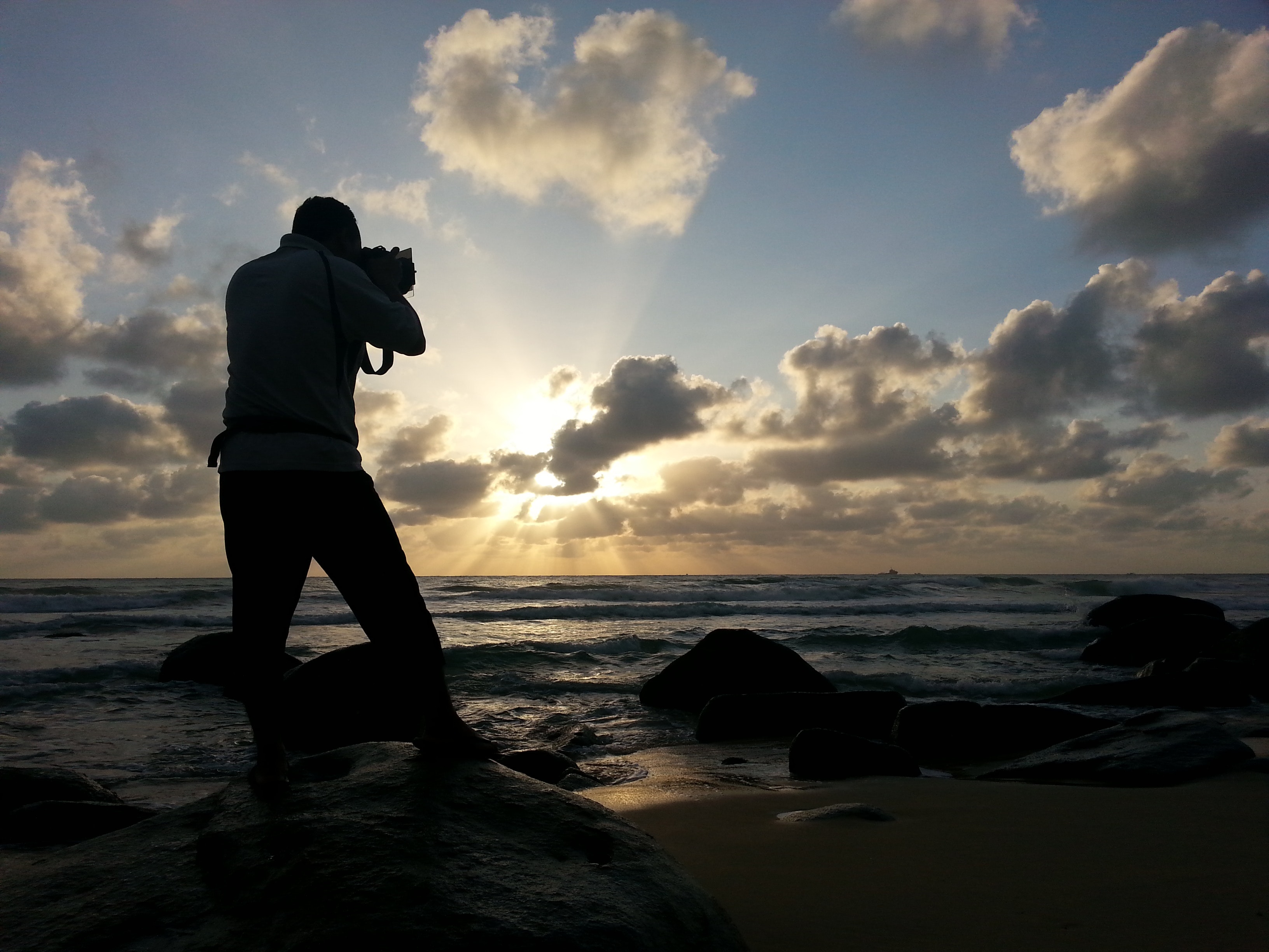 Person capturing photo near sea under clear blue and white cloudy sky during daytime