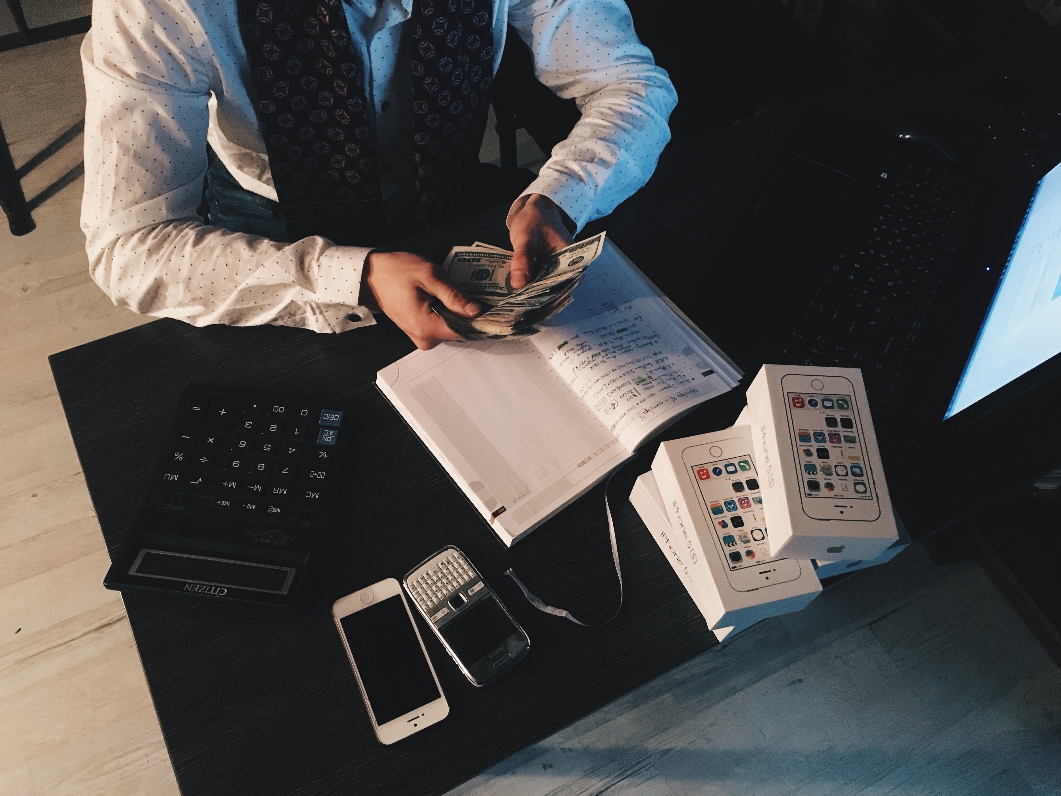 Person counting money with smartphones in front on desk photo
